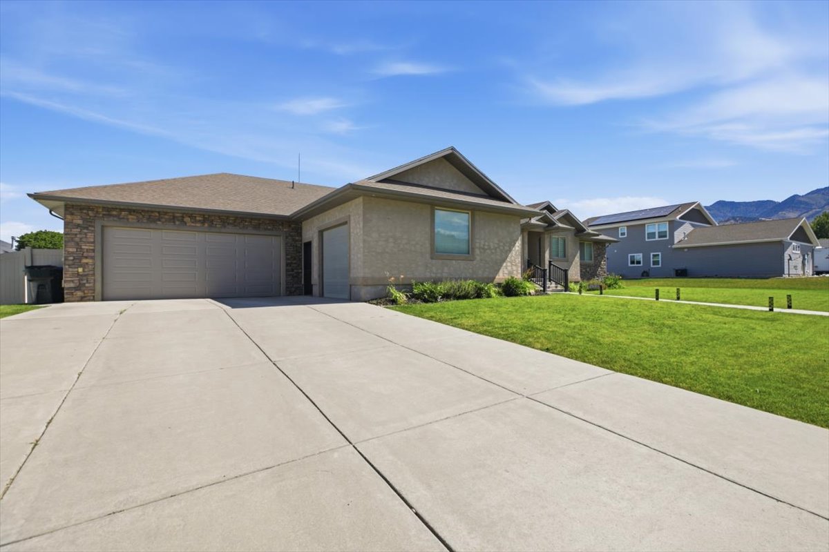 Contemporary ranch-style residence featuring a textured stucco exterior, stone facade accents, and a dual garage