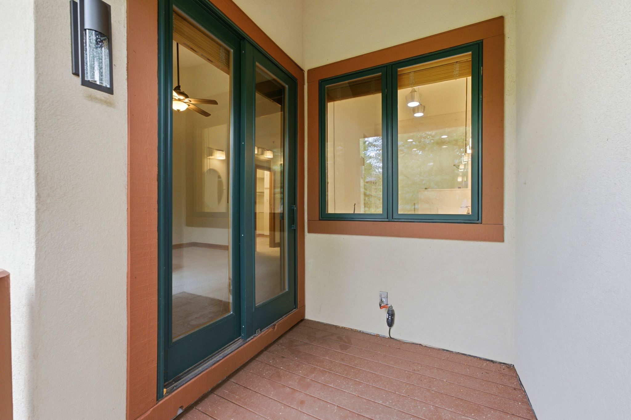 Outdoor patio featuring wood-finish flooring, stucco exterior, and a contemporary wall-mounted light fixture