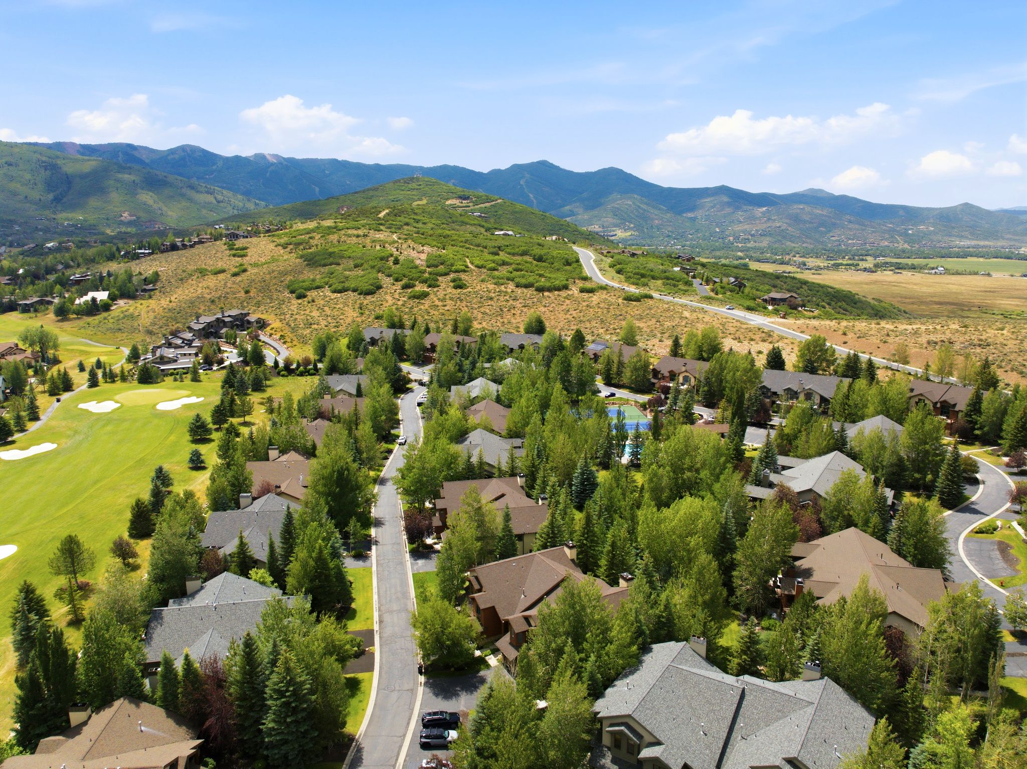 Expansive aerial showcasing a residential community nestled among rolling hills and mature trees