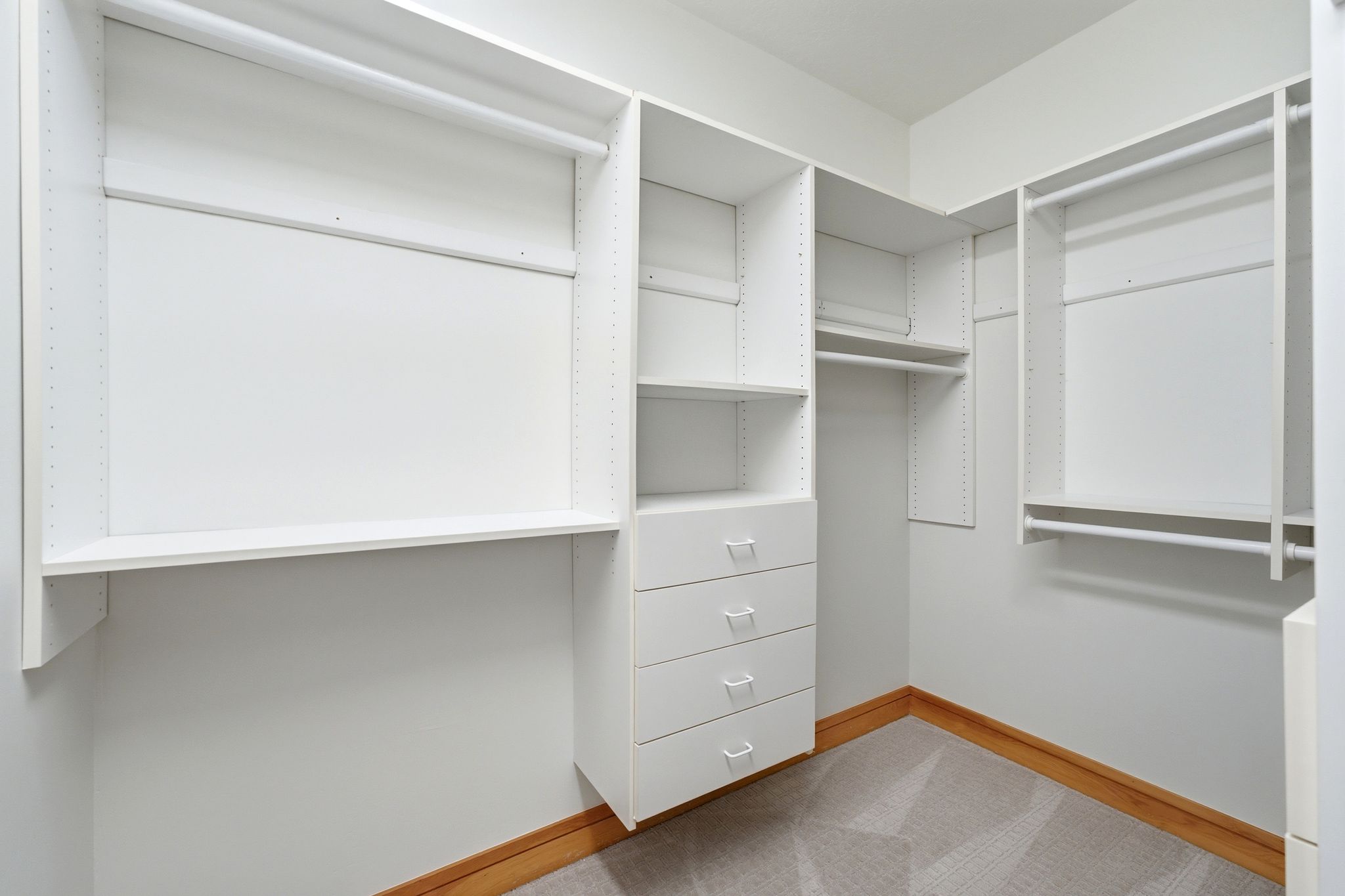 Walk-in closet featuring white built-in cabinetry, multiple hanging rods, shelving, and four integrated drawers