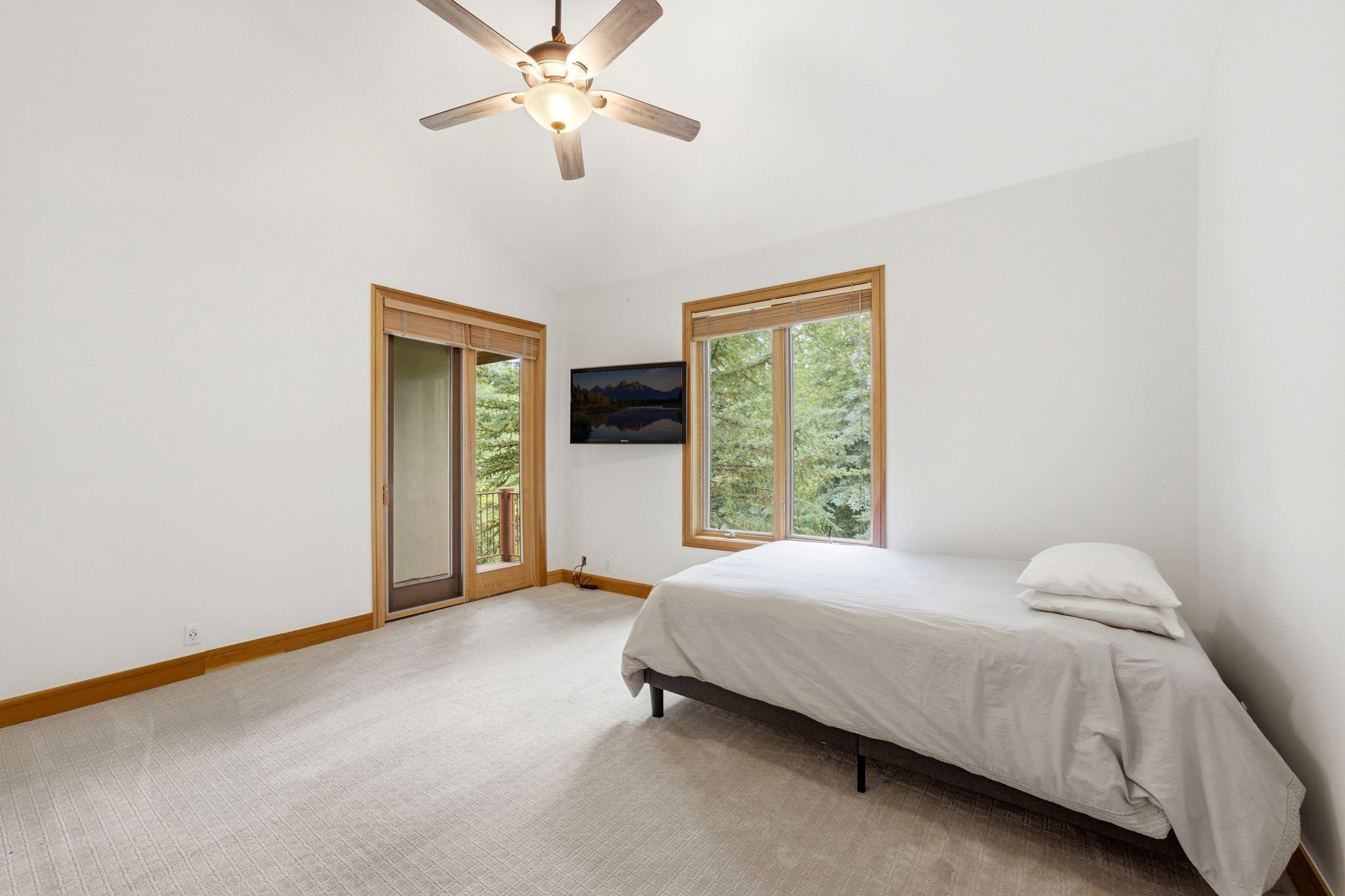Vaulted ceiling room featuring light-colored carpet flooring, a ceiling fan, and white walls
