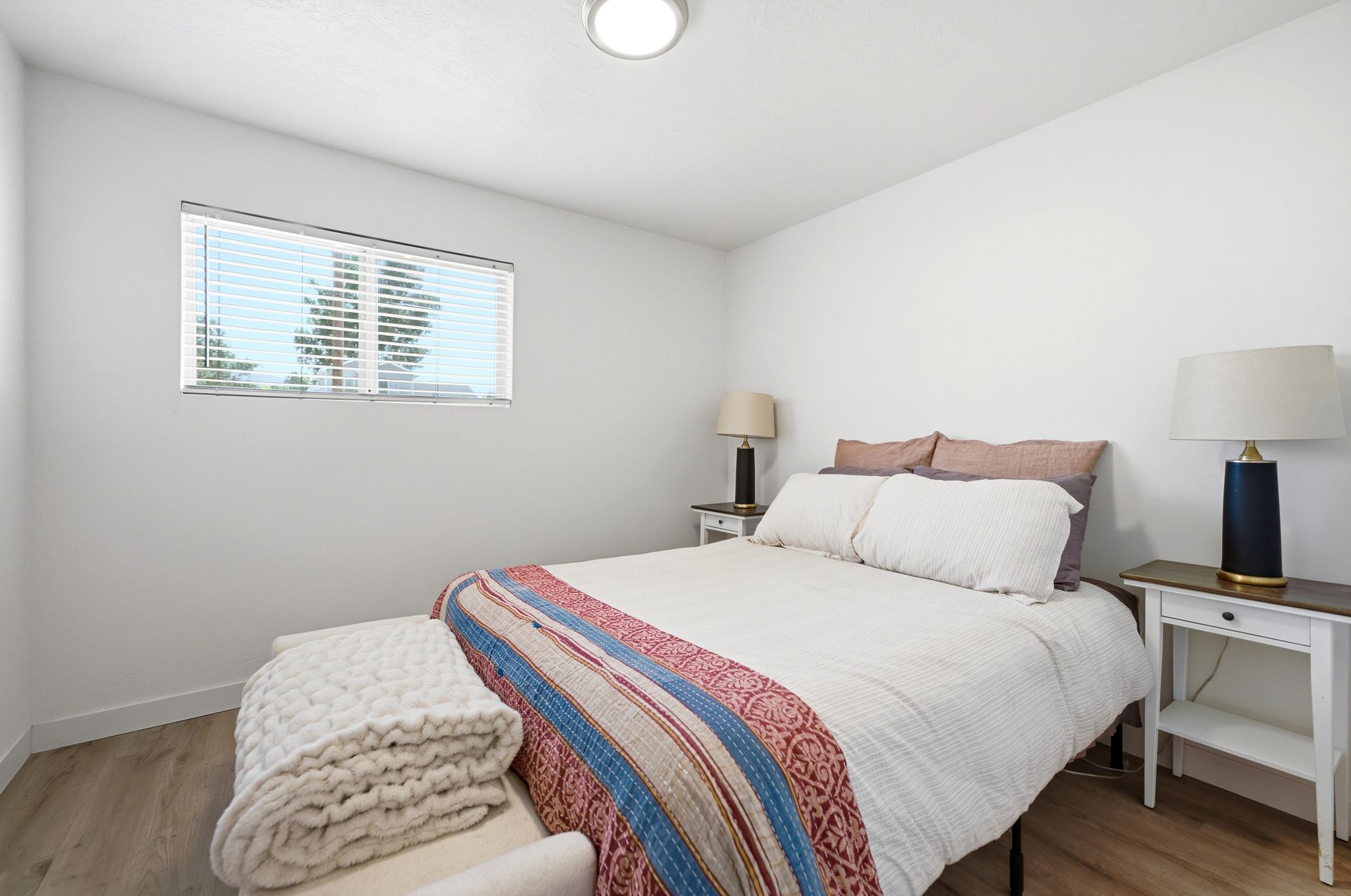 Bright bedroom featuring light wood-finish flooring, white walls, and a recessed ceiling light