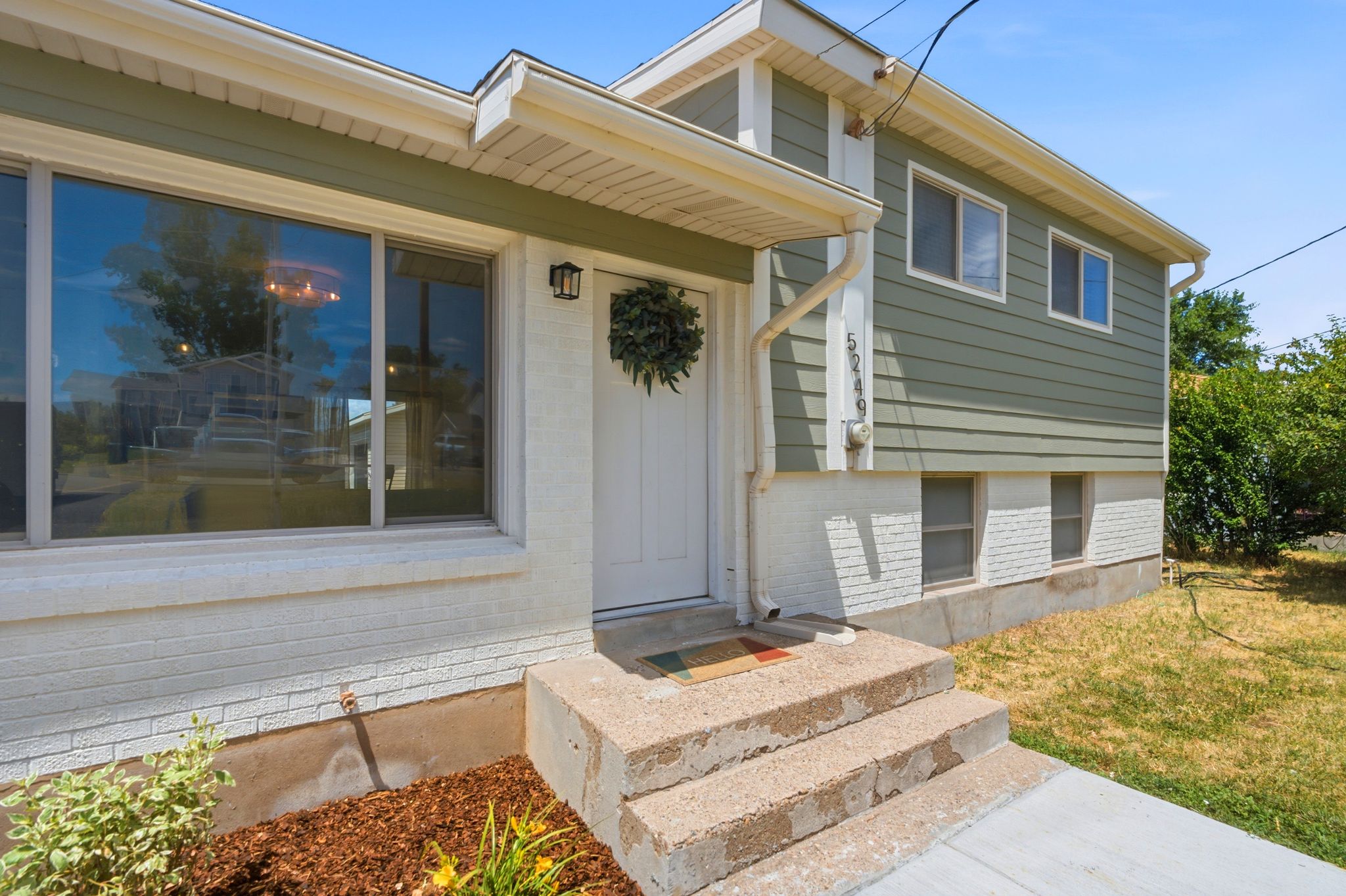 Two-story exterior with light green siding and white brick foundation