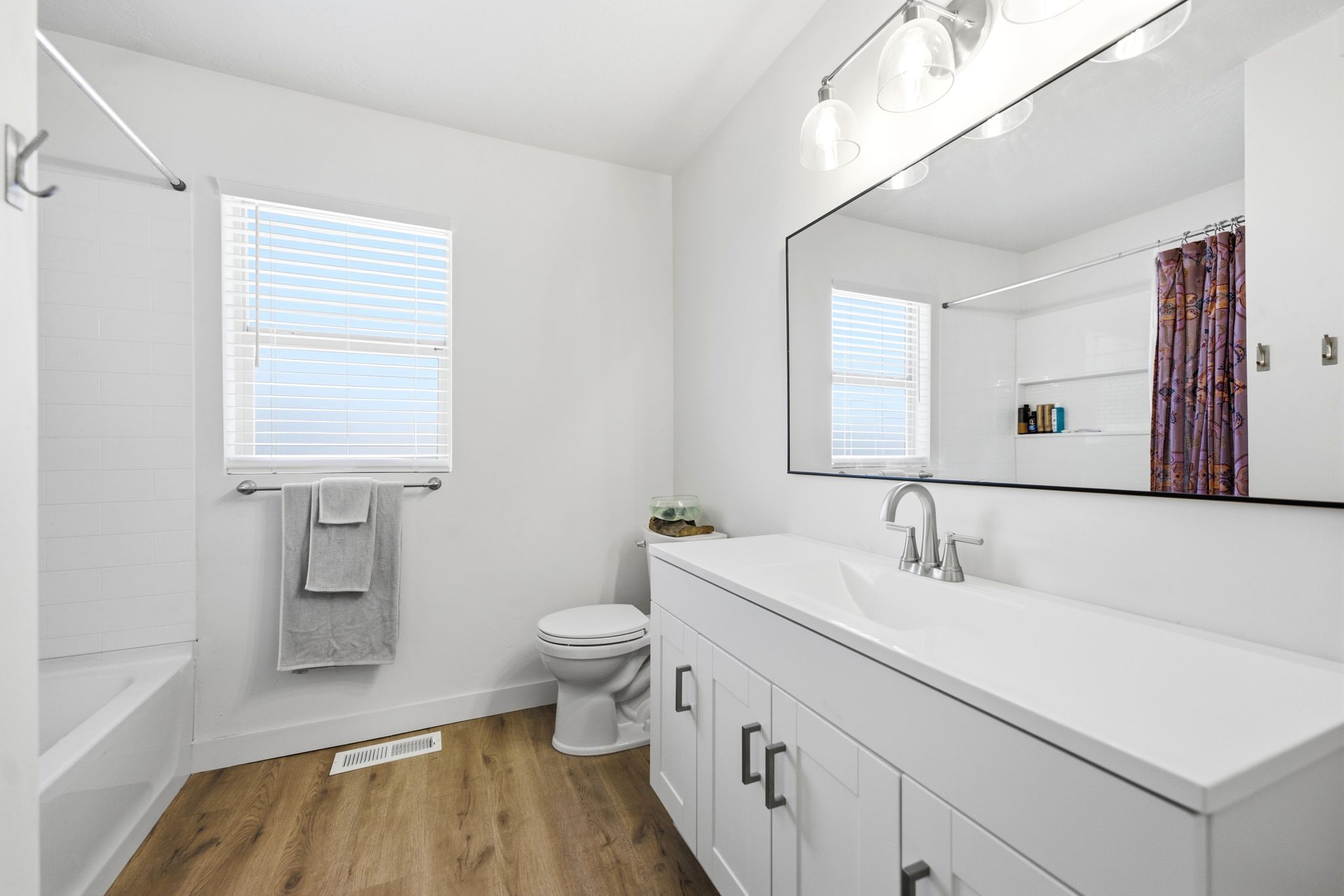 Bathroom featuring a white vanity with integrated sink, chrome faucet, and expansive mirror