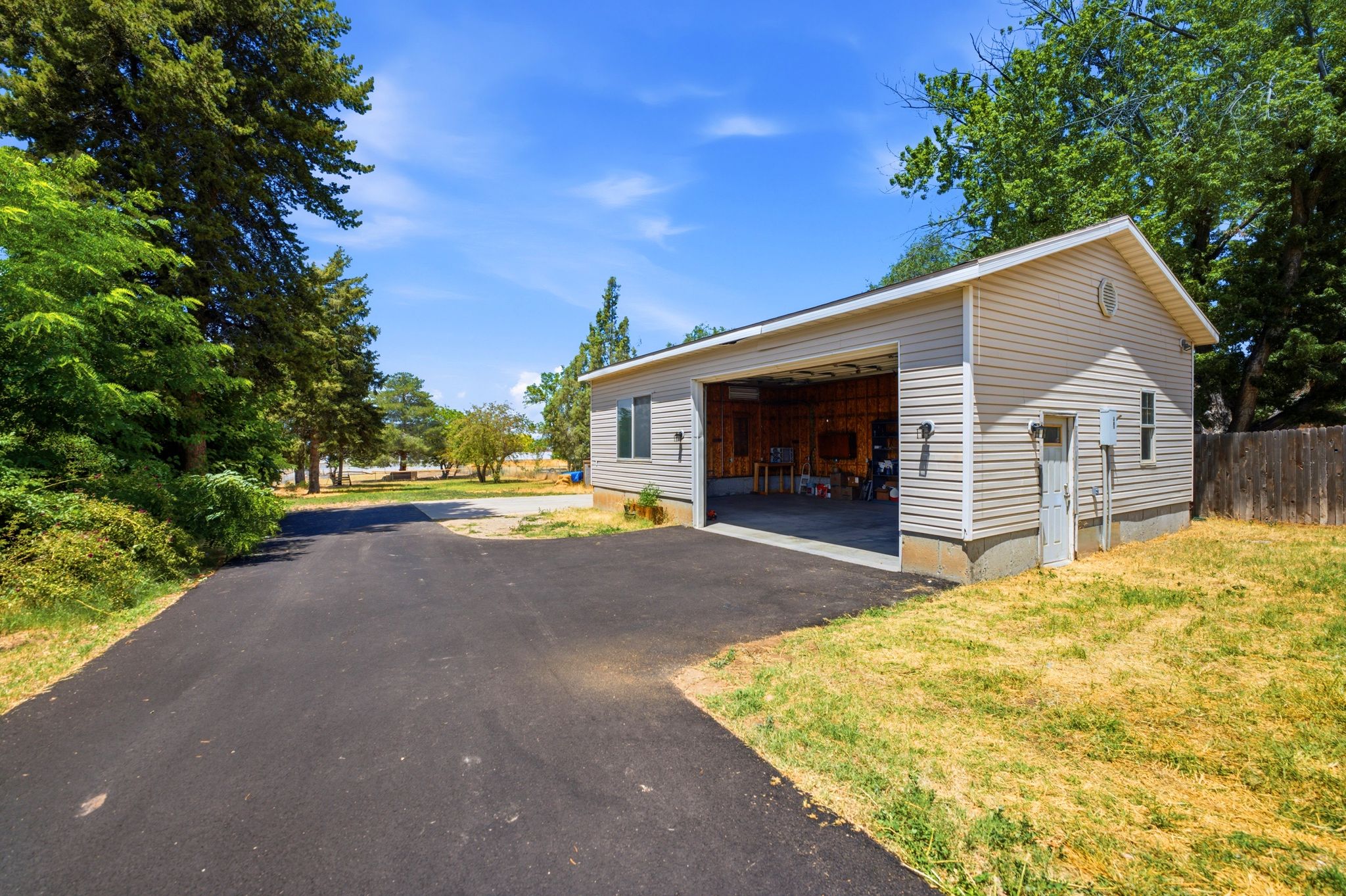 Detached garage structure featuring light-colored siding, a pitched roof, and a large open bay entrance