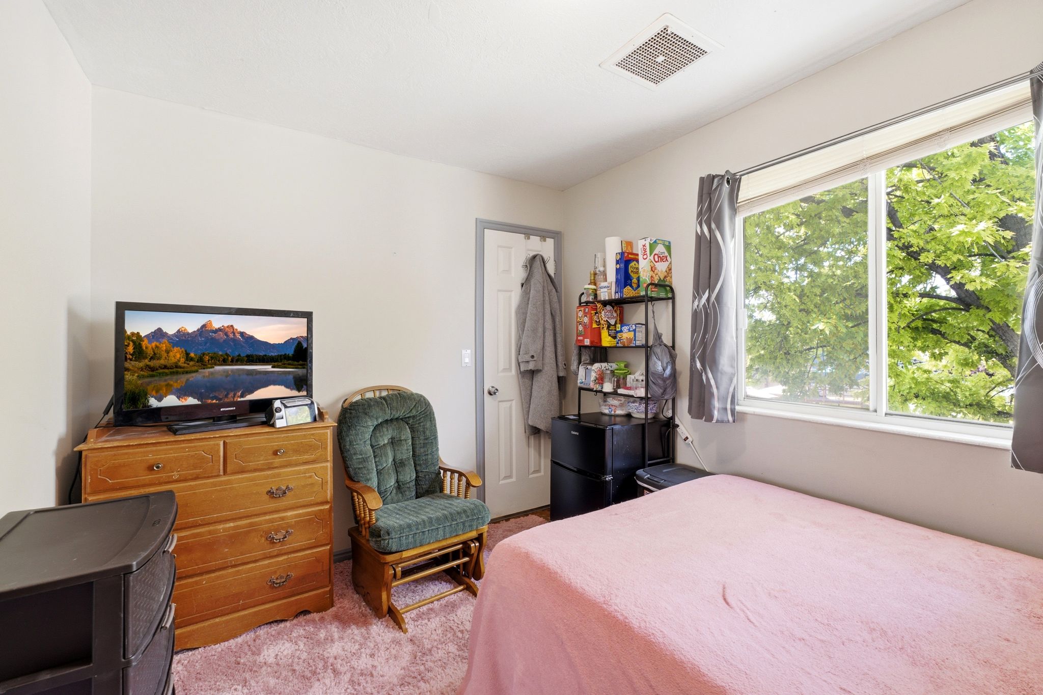 Light-filled interior space featuring a large window, neutral wall paint, and a white ceiling with a central vent