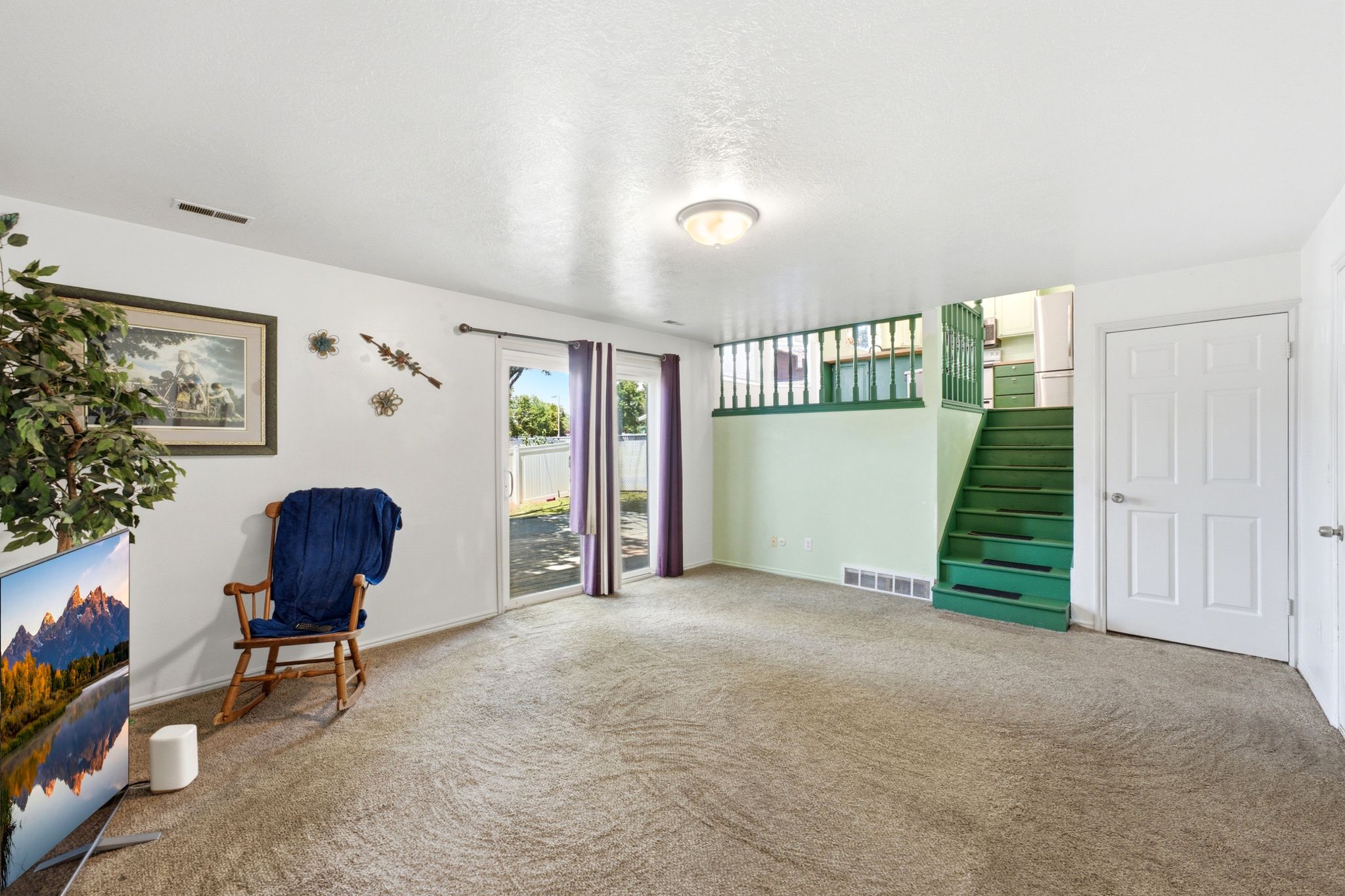 Carpeted living area featuring white walls and a ceiling light fixture
