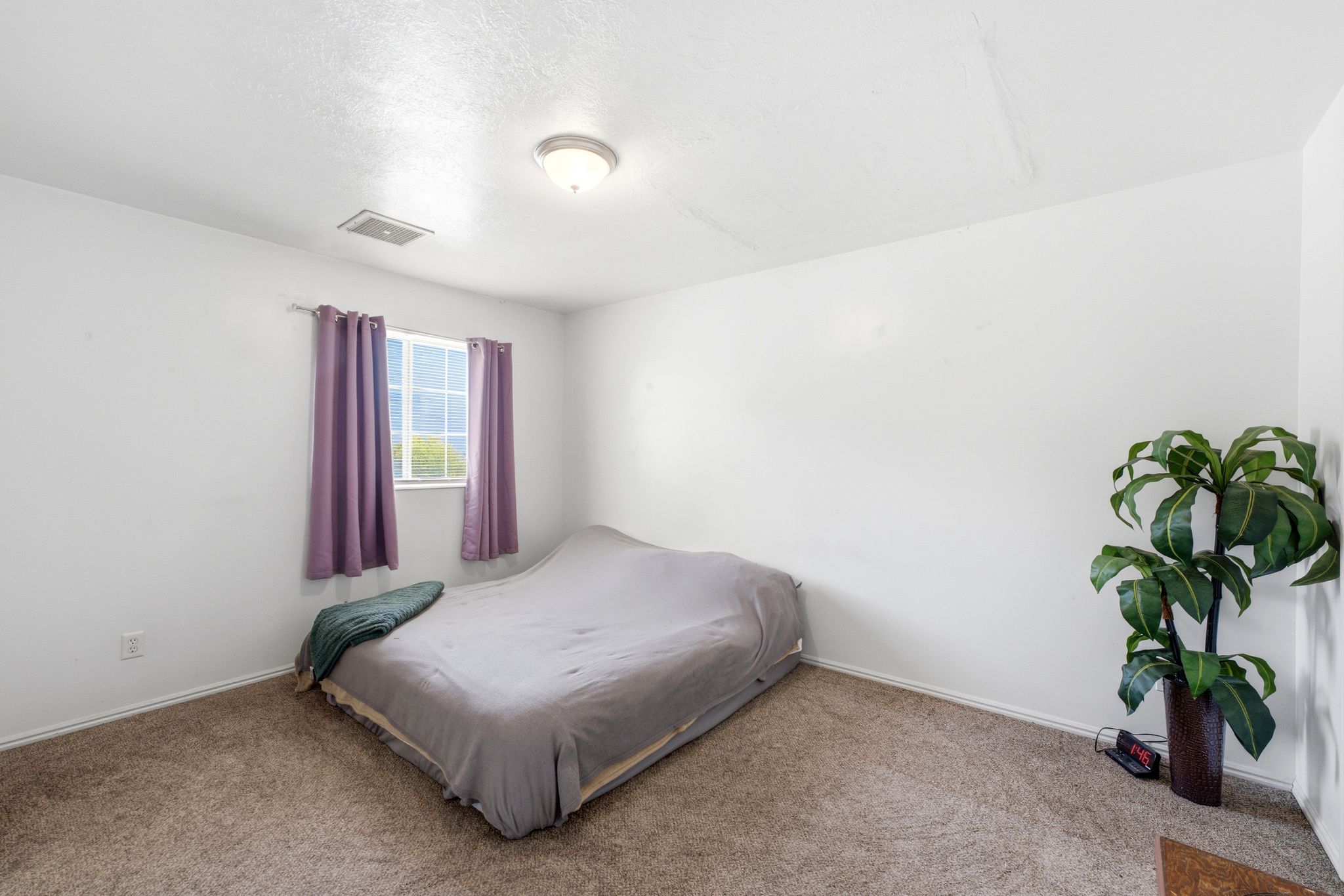 Carpeted room featuring a window with vertical blinds, a ceiling-mounted light fixture, and white painted walls