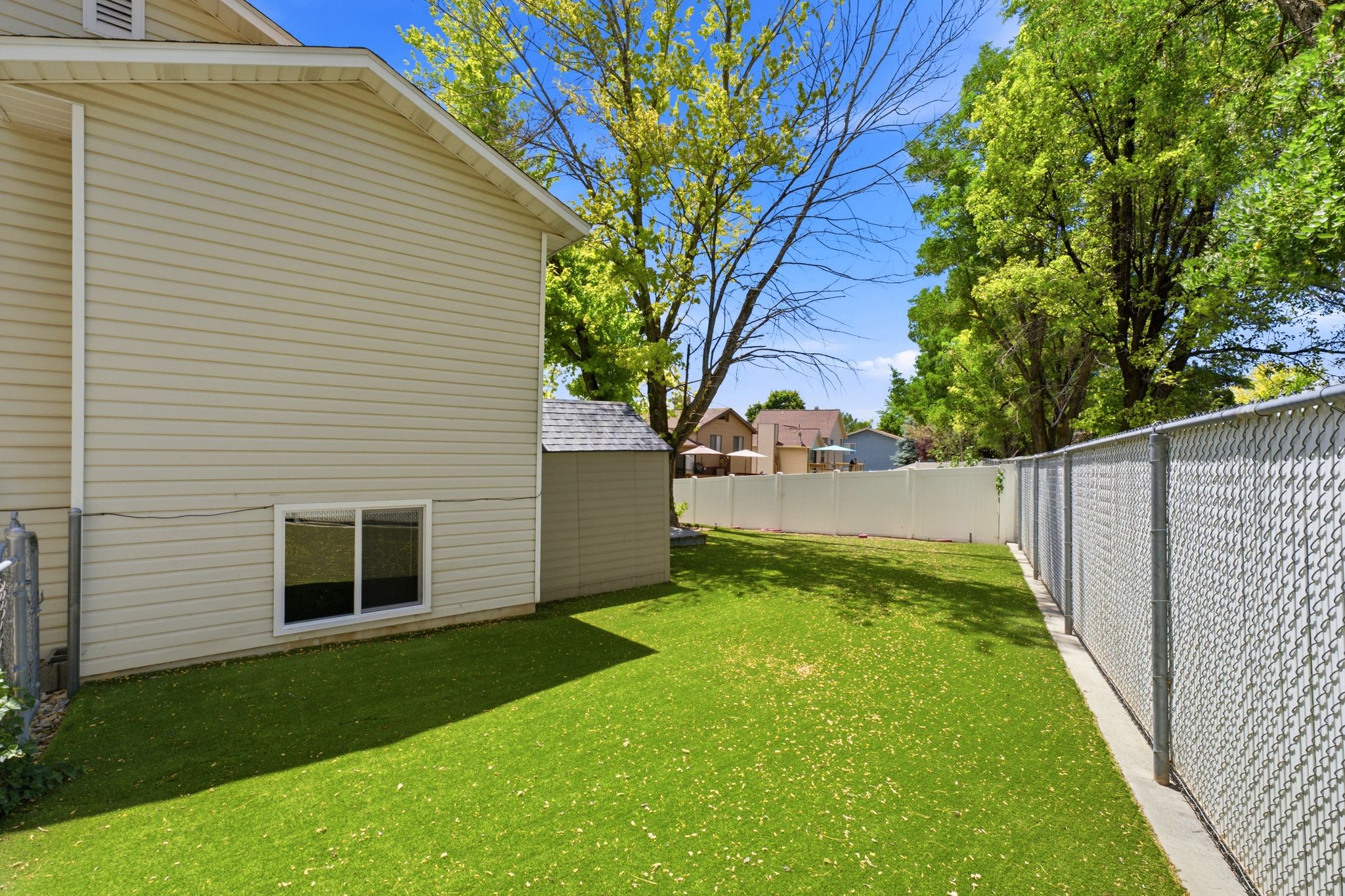 Expansive backyard featuring a manicured lawn, a chain-link fence, and a privacy fence