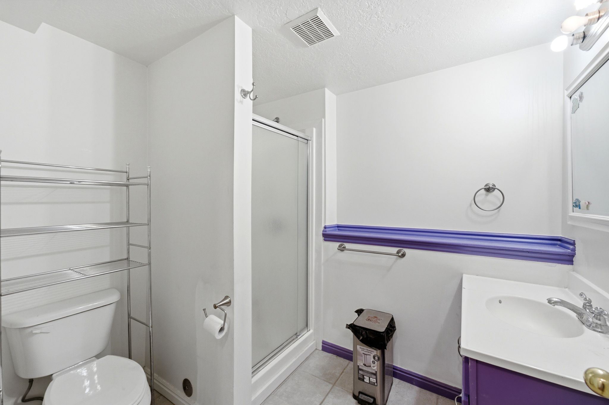 Bathroom featuring a glass-enclosed shower, single vanity with a white basin, and a toilet