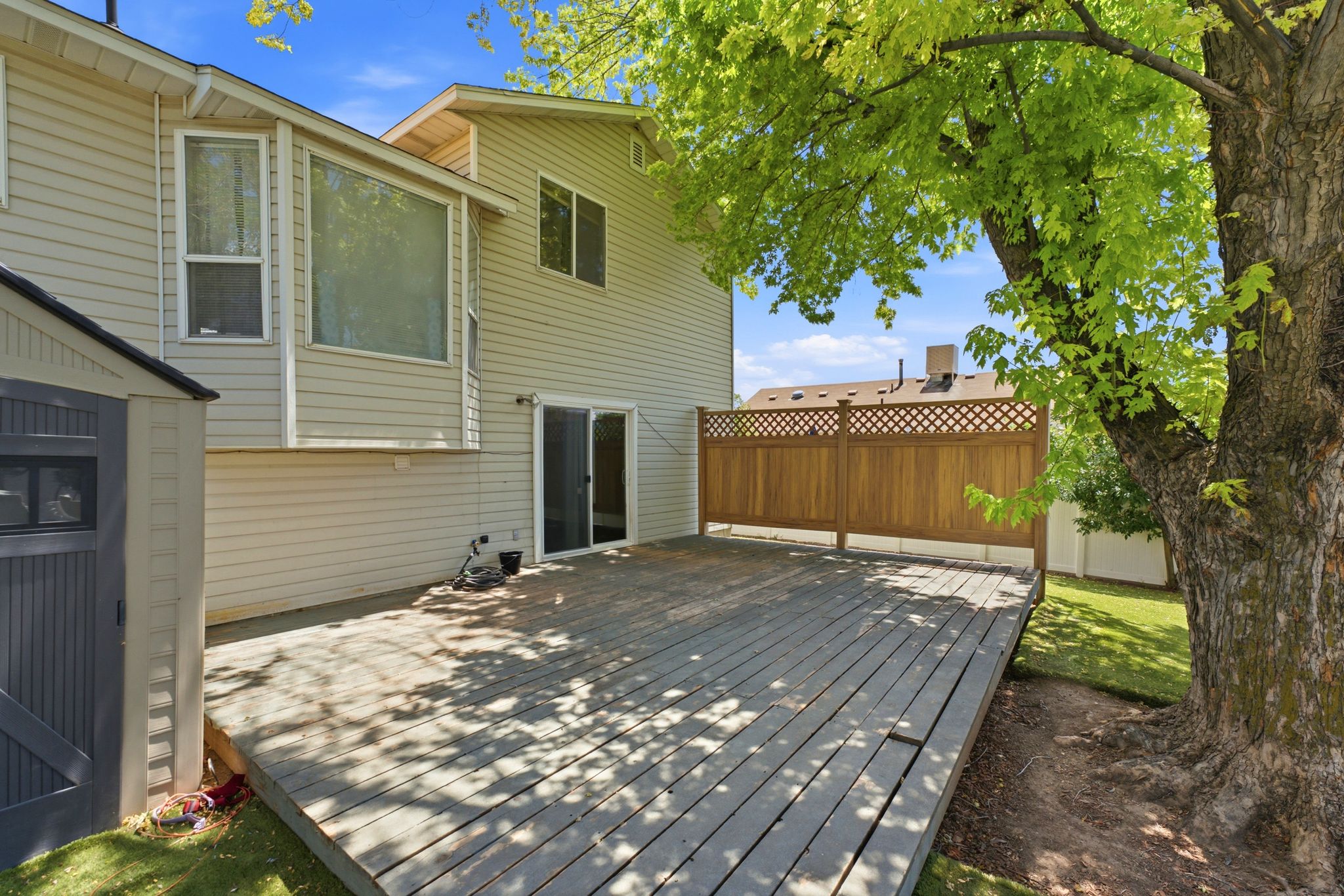 Spacious outdoor deck featuring wood flooring and a privacy lattice fence