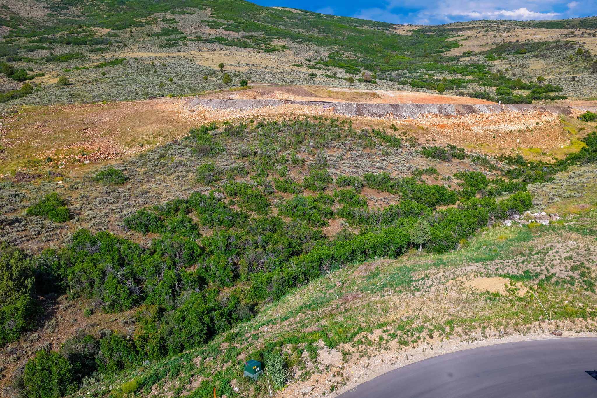 Undulating terrain featuring varied vegetation, natural rock formations, and paved road access