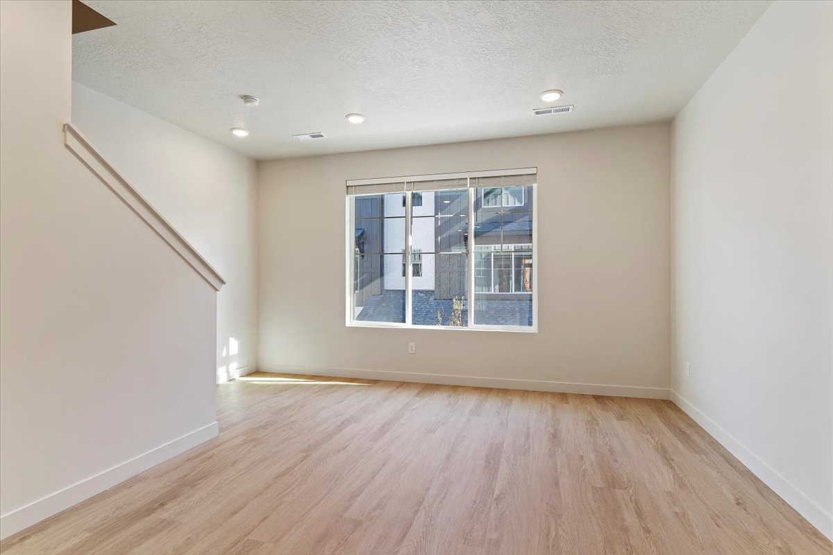 Spacious room featuring light wood-finish flooring, recessed lighting, and a large window with white trim