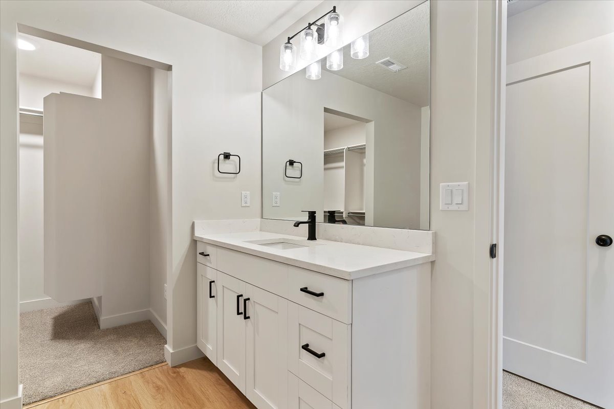 Bathroom vanity featuring a white shaker-style cabinet with matte black hardware, a white countertop, and a rectangular undermount sink with a matte black faucet