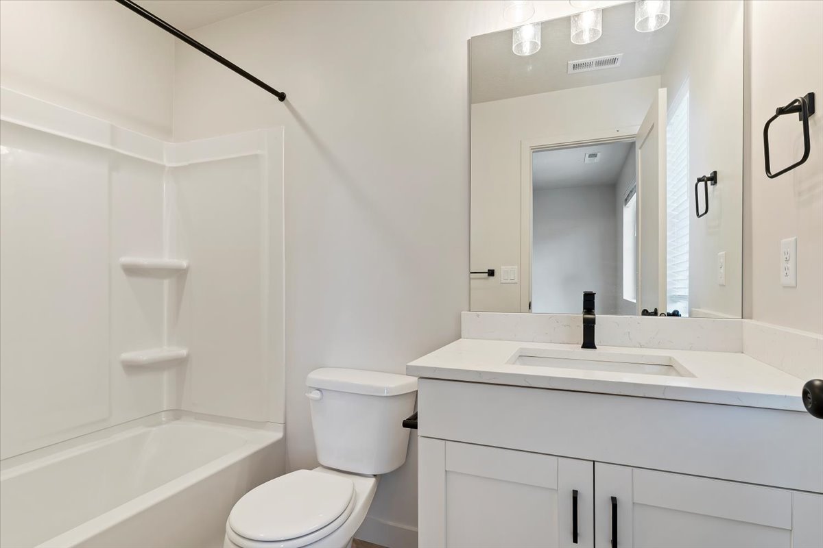 Bathroom featuring a white vanity with a light-colored countertop, an integrated rectangular sink, and a matte black faucet
