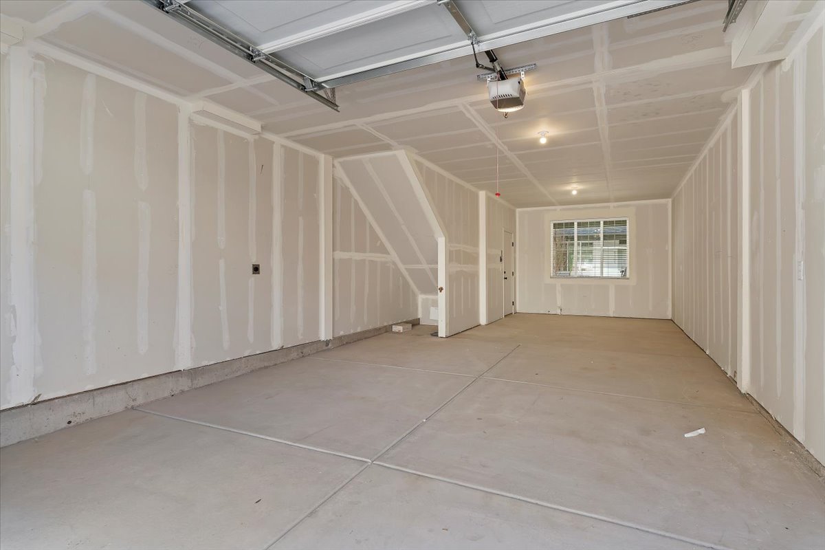 Spacious garage with unfinished drywall, concrete flooring, and an overhead garage door mechanism