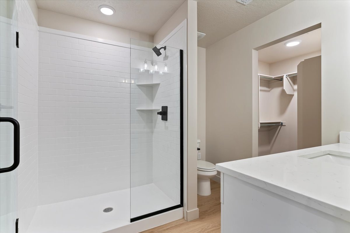 Modern bathroom featuring a glass-enclosed shower with subway tile surround, matte black fixtures, and built-in shelving