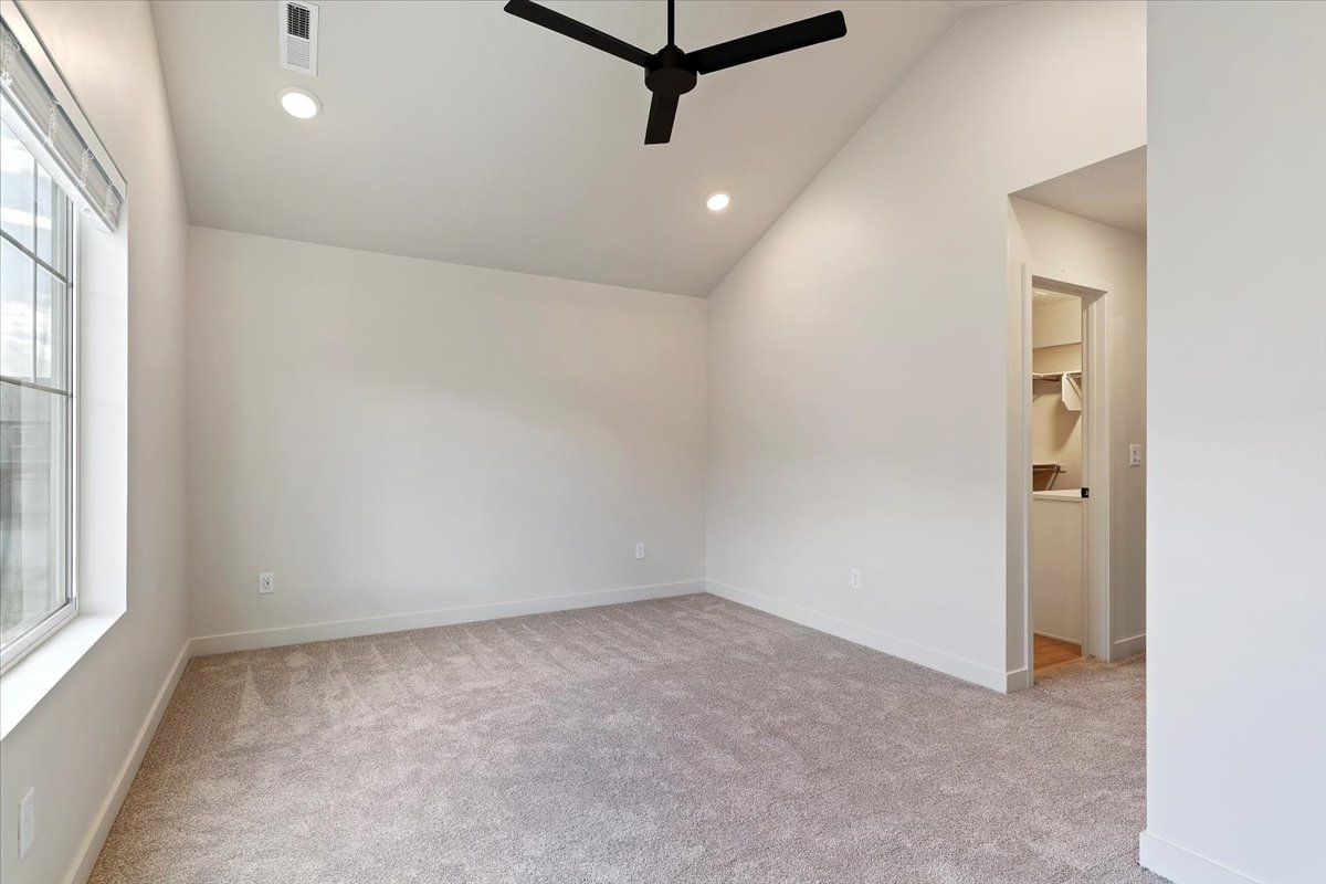 Carpeted room featuring a vaulted ceiling with a black ceiling fan, recessed lighting, and a large window