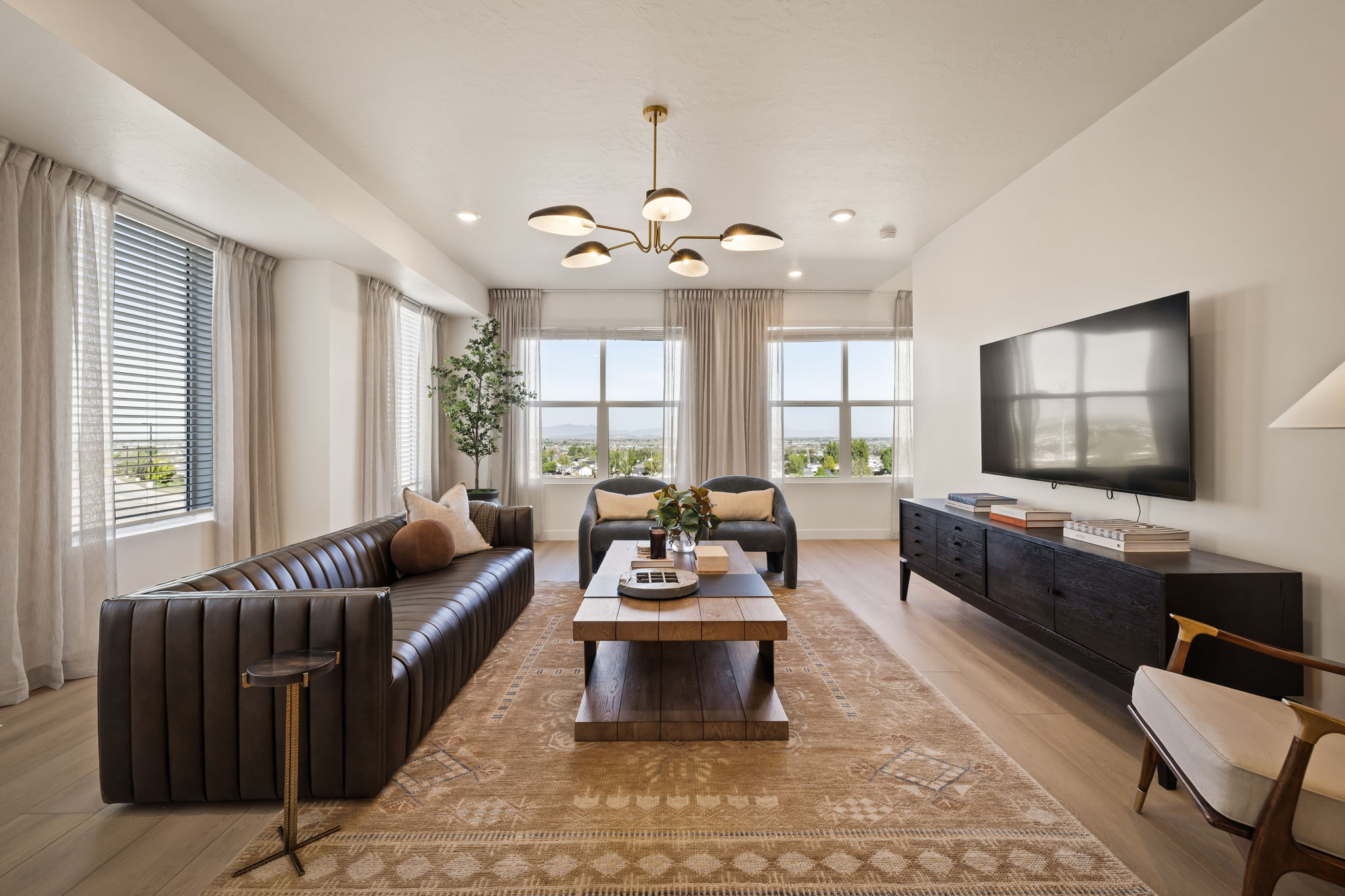 Open-concept living area featuring light wood-finish flooring, recessed lighting, and a contemporary chandelier