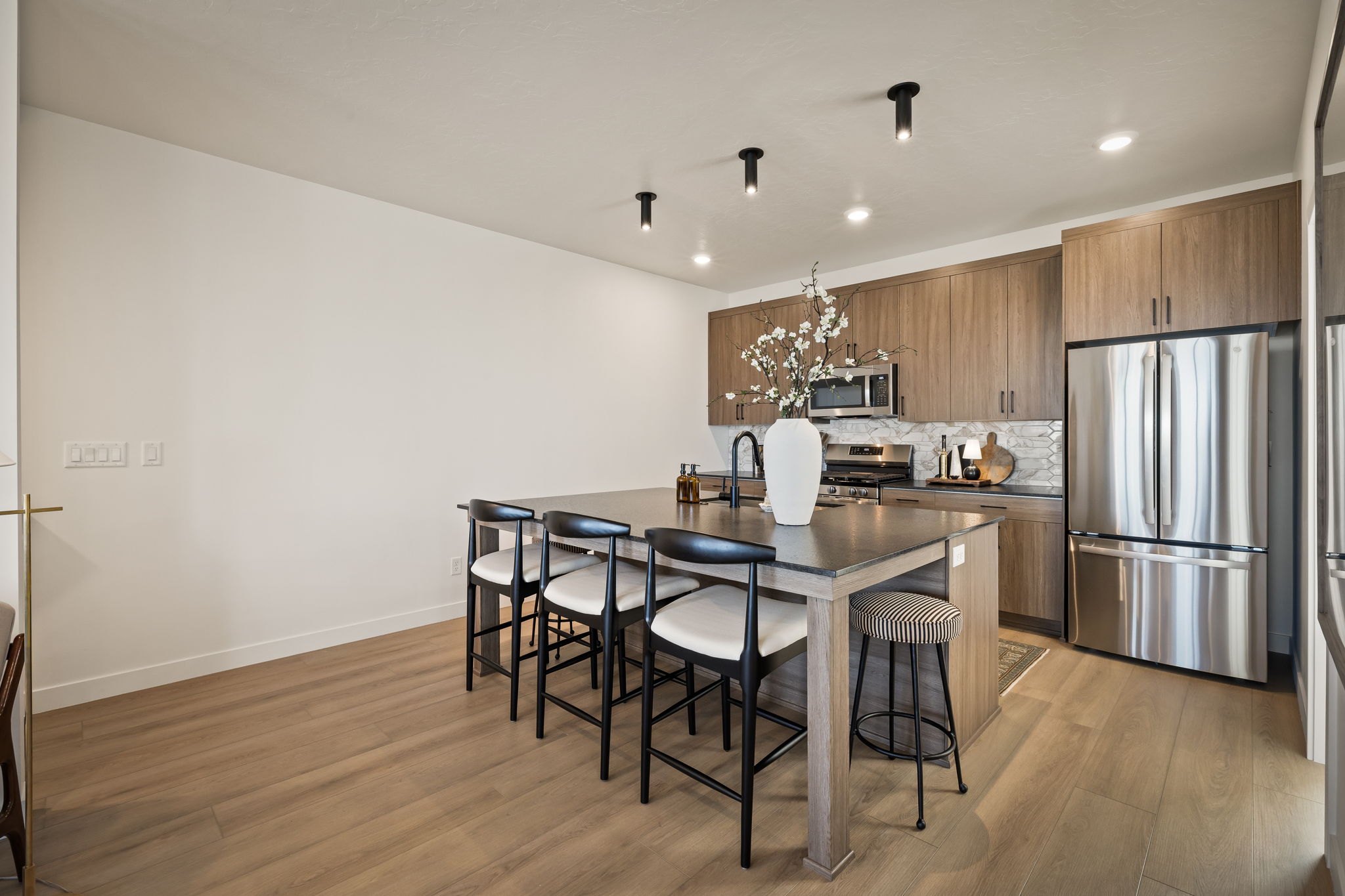 Modern kitchen featuring wood-finish flooring, a central island with countertop seating, wood-grain cabinetry, and stainless steel appliances
