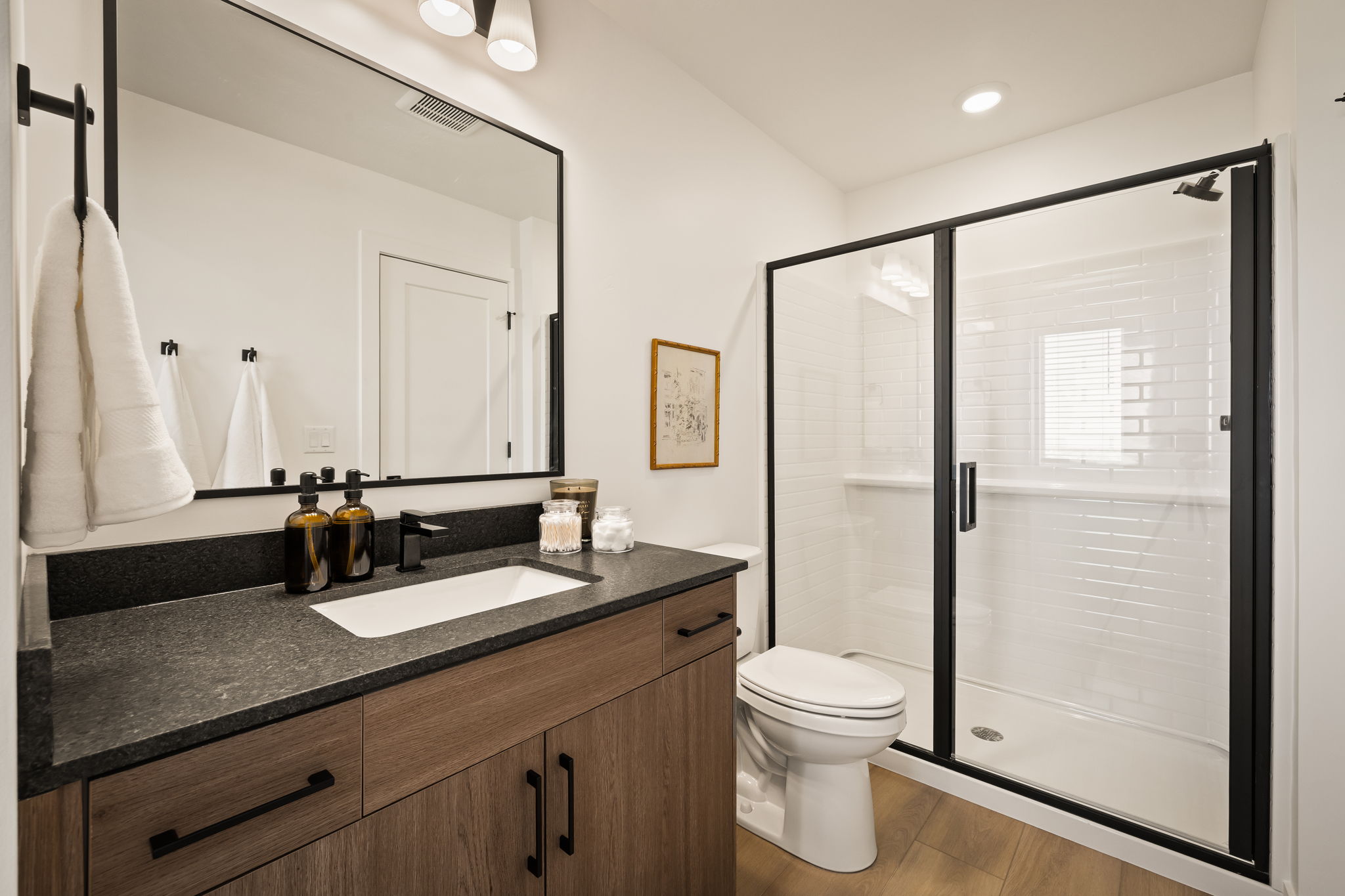 Bathroom featuring a wood-finish vanity with a rectangular undermount sink, dark countertop, and matte black faucet