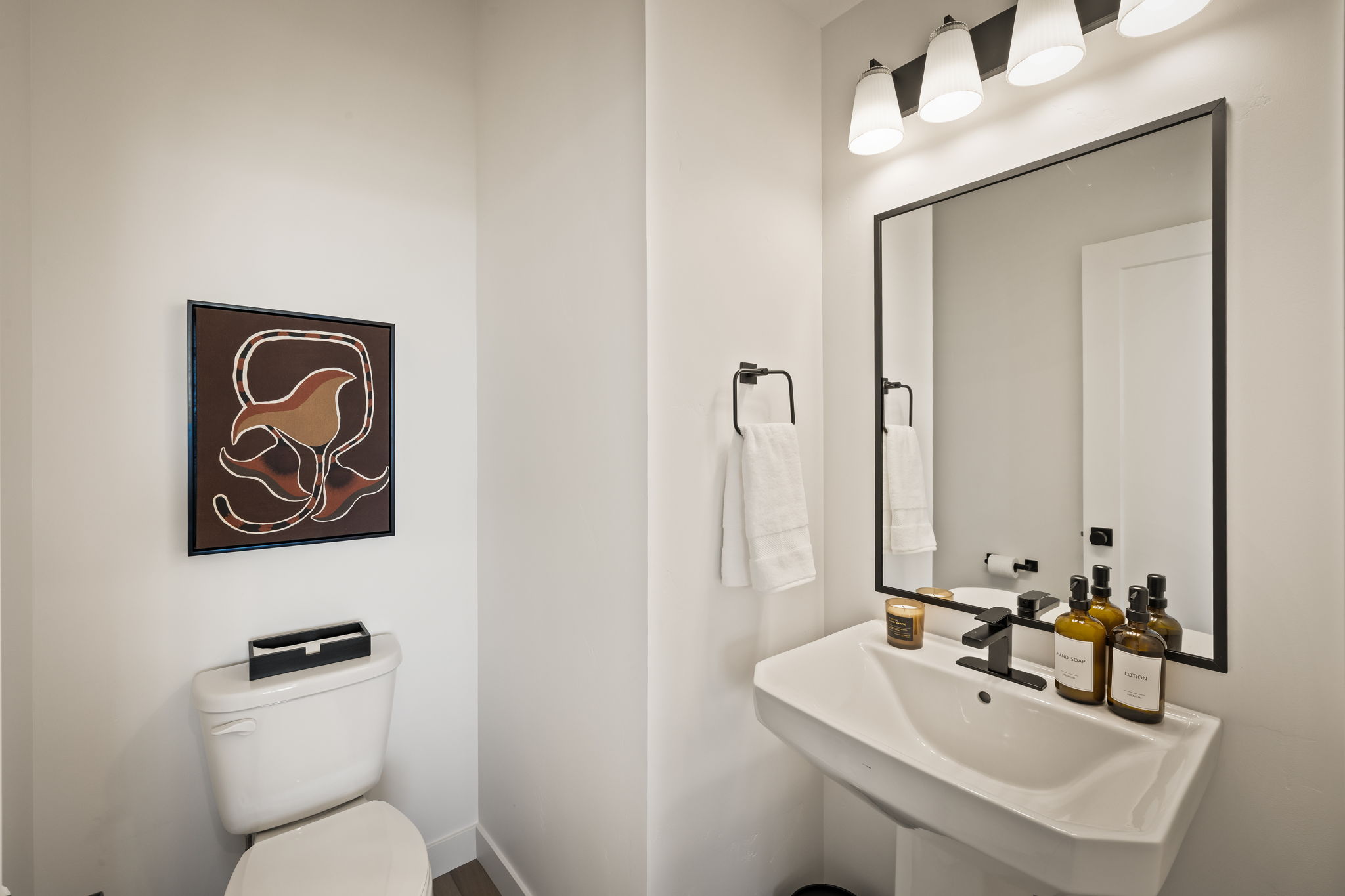 Modern bathroom featuring a pedestal sink, matte black faucet, and a rectangular mirror with a black frame