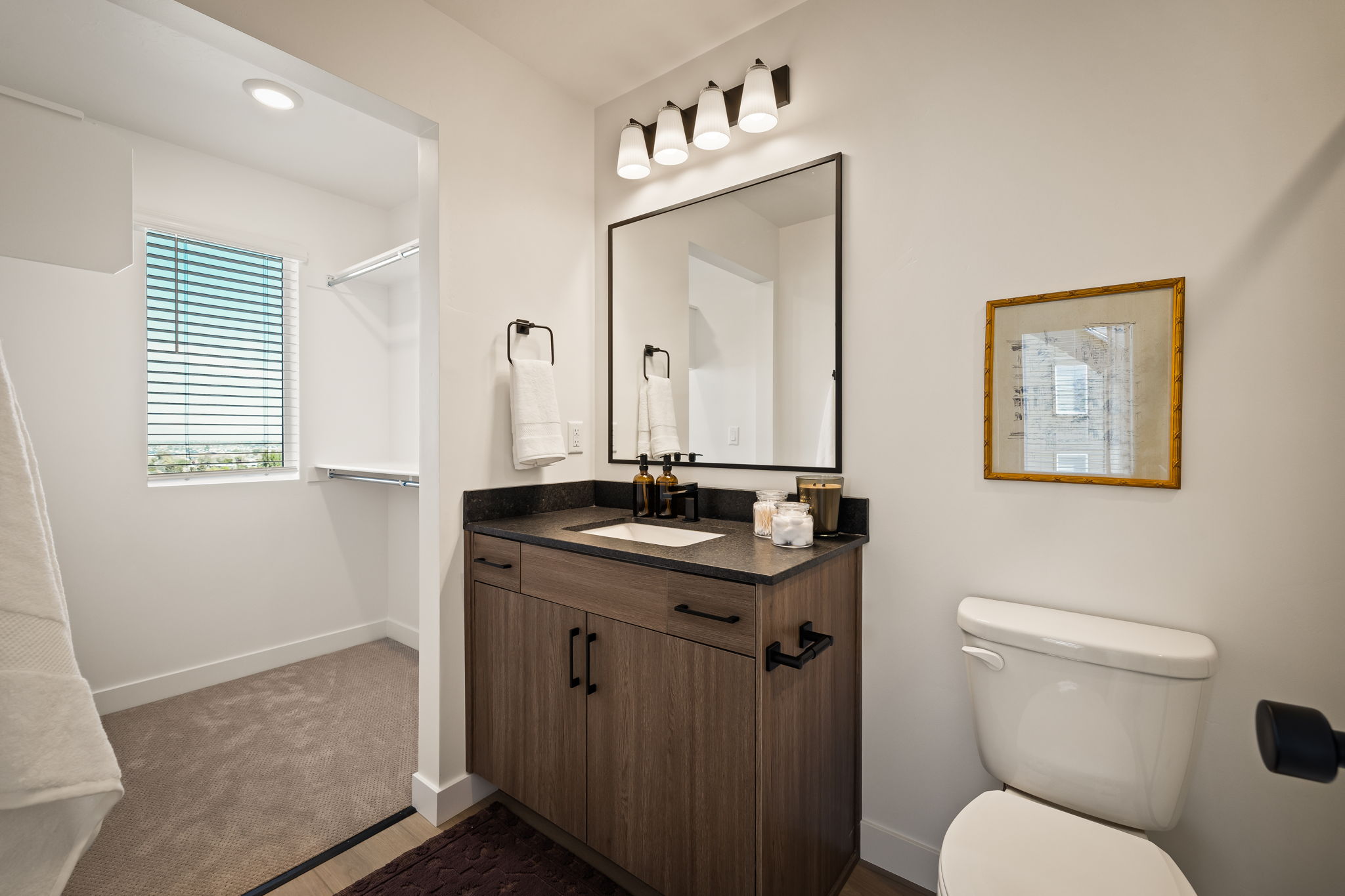 Bathroom featuring a wood-finish vanity with a dark countertop, white undermount sink, and black hardware