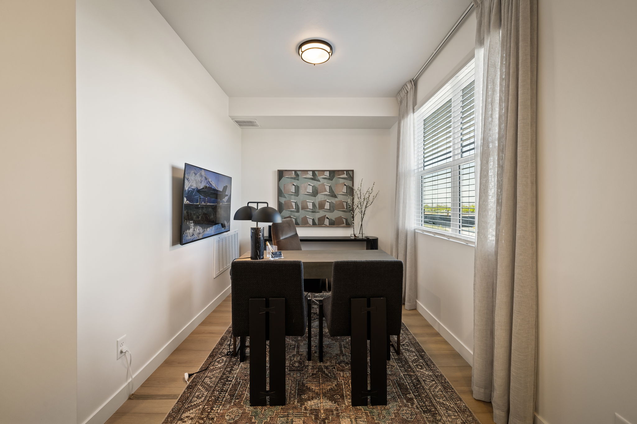 Dedicated office space featuring wood-finish flooring, a contemporary flush mount ceiling light, and a large window with blinds