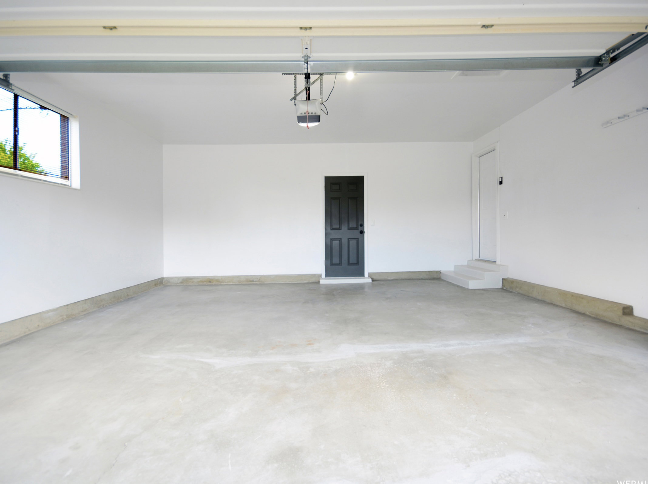 Spacious garage featuring a concrete floor, bright white walls, and a window for natural light