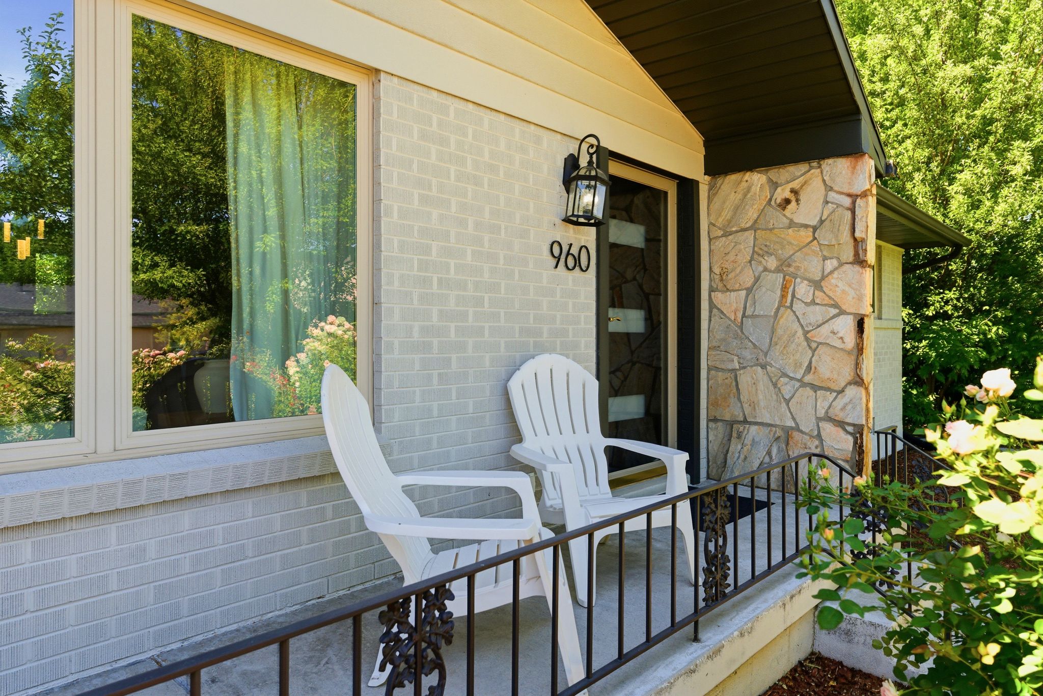 Front entry featuring a stone facade accent, light brick siding, and a covered porch