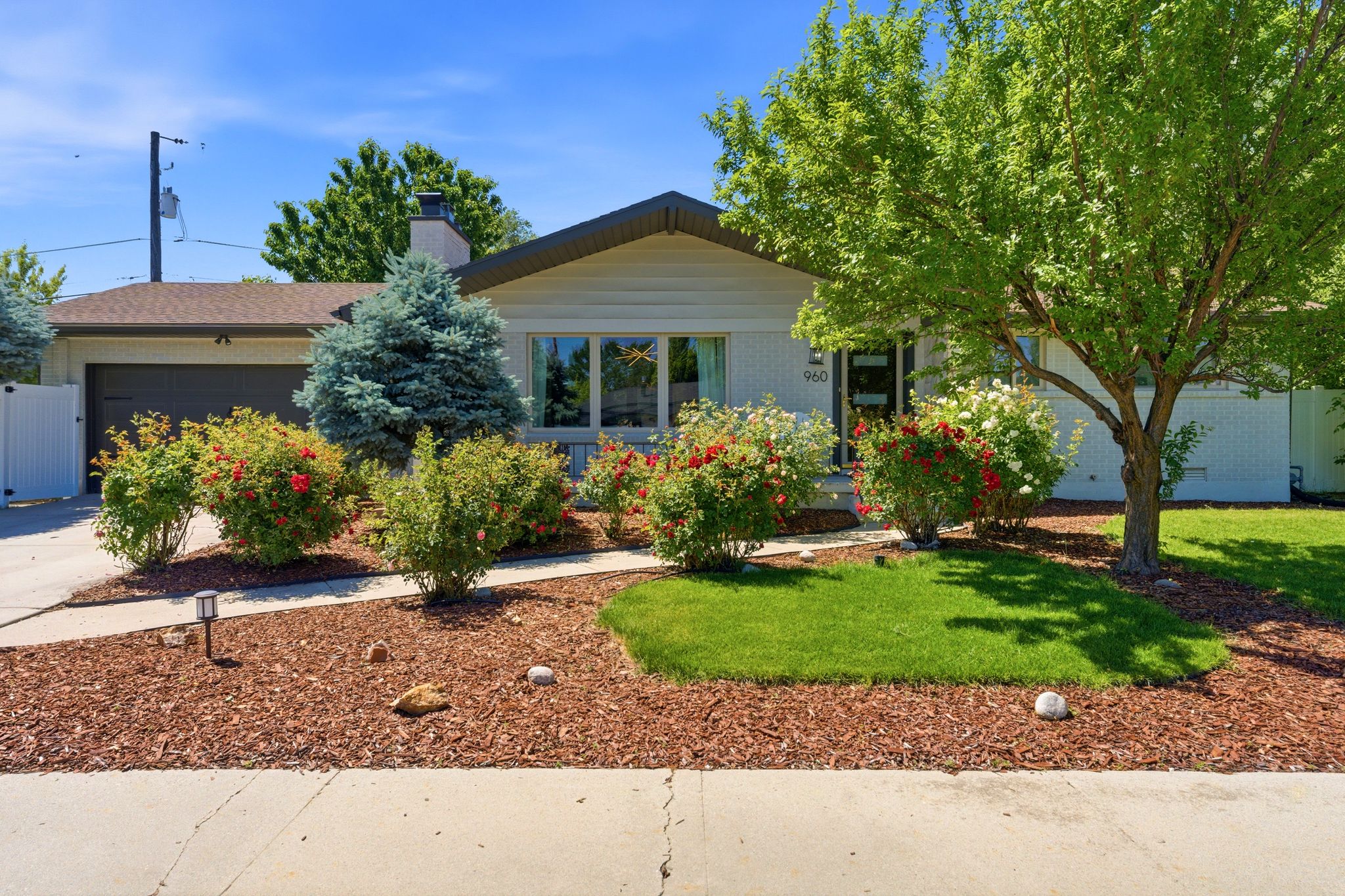 Front exterior featuring a dark garage door, white privacy fence, and a stone chimney