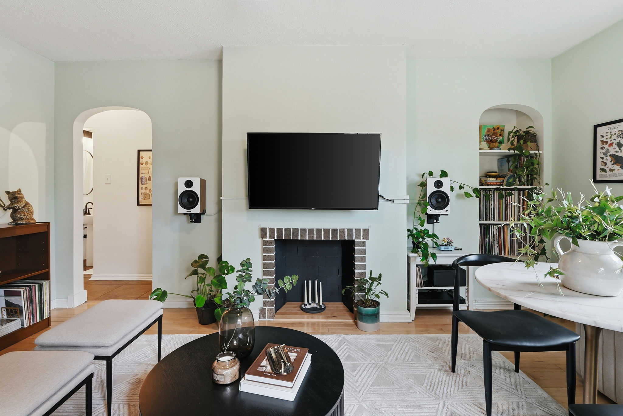 Living area featuring a central fireplace with a brick surround, light wood-finish flooring, and arched doorways