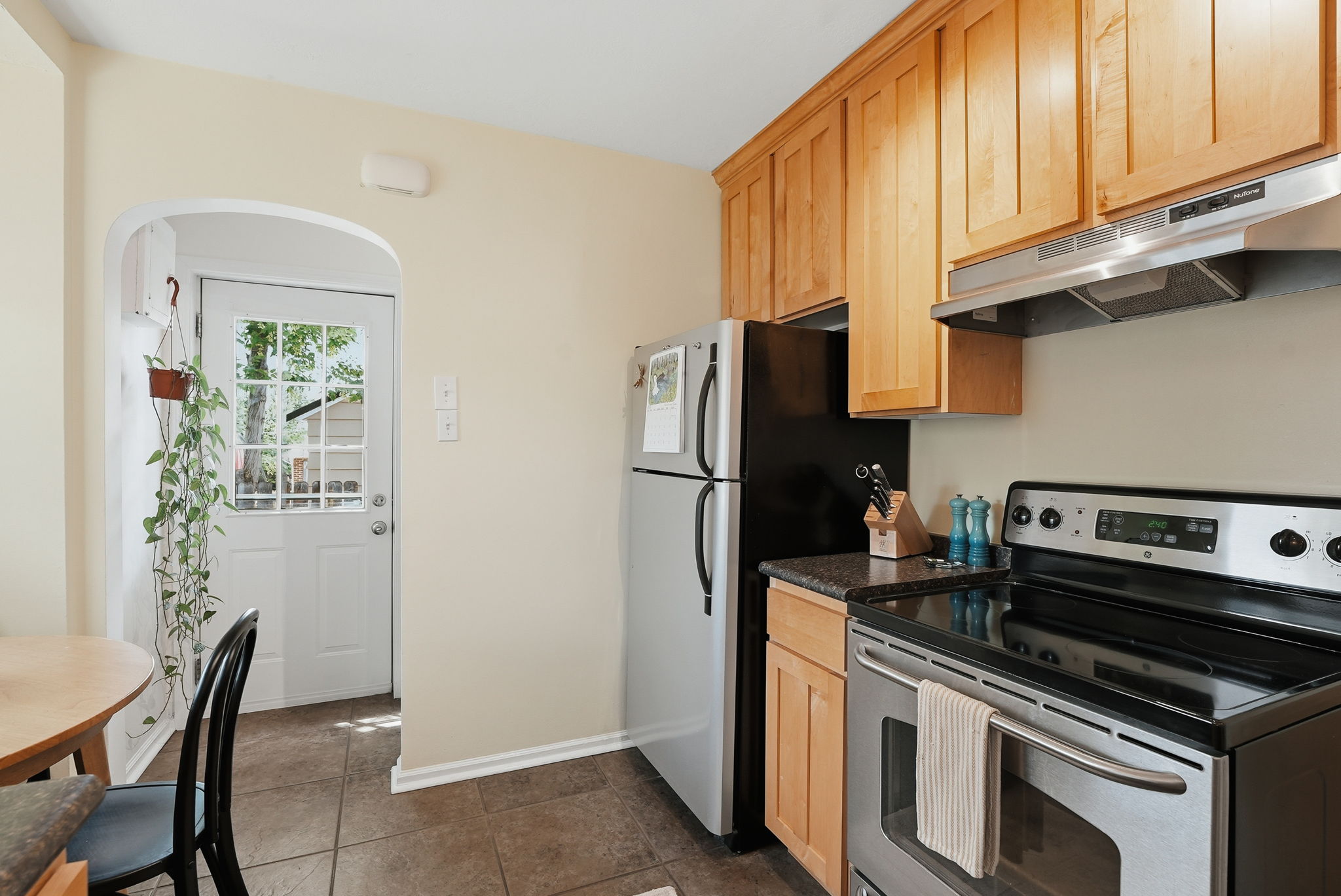 Kitchen featuring light wood cabinetry, dark countertops, and stainless steel appliances