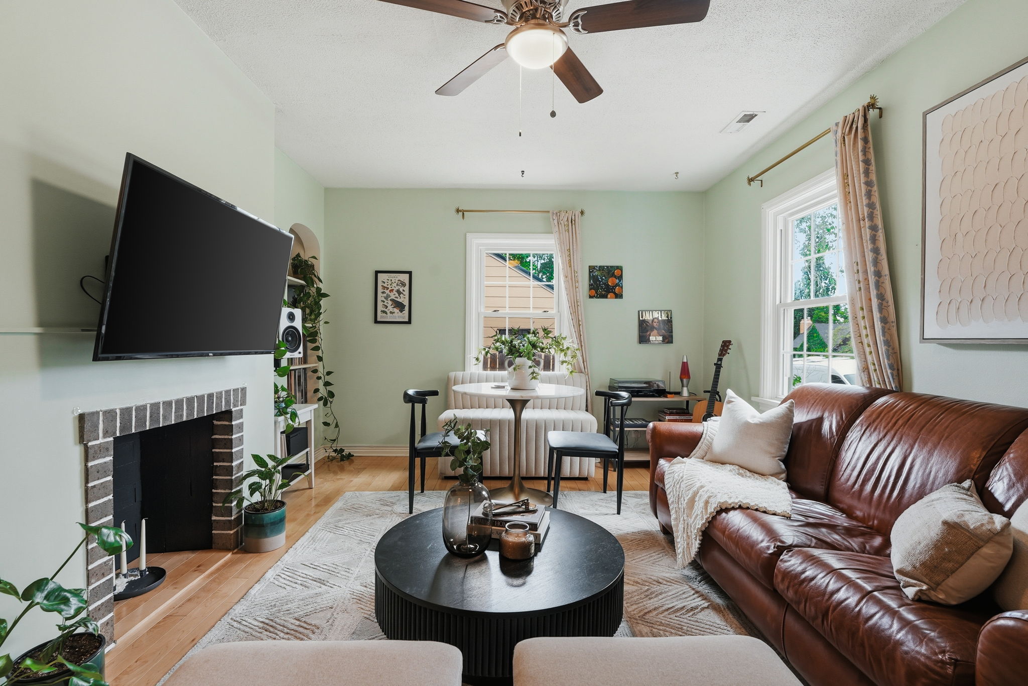 Living area featuring wood-finish flooring, a ceiling fan with integrated lighting, and multiple double-hung windows