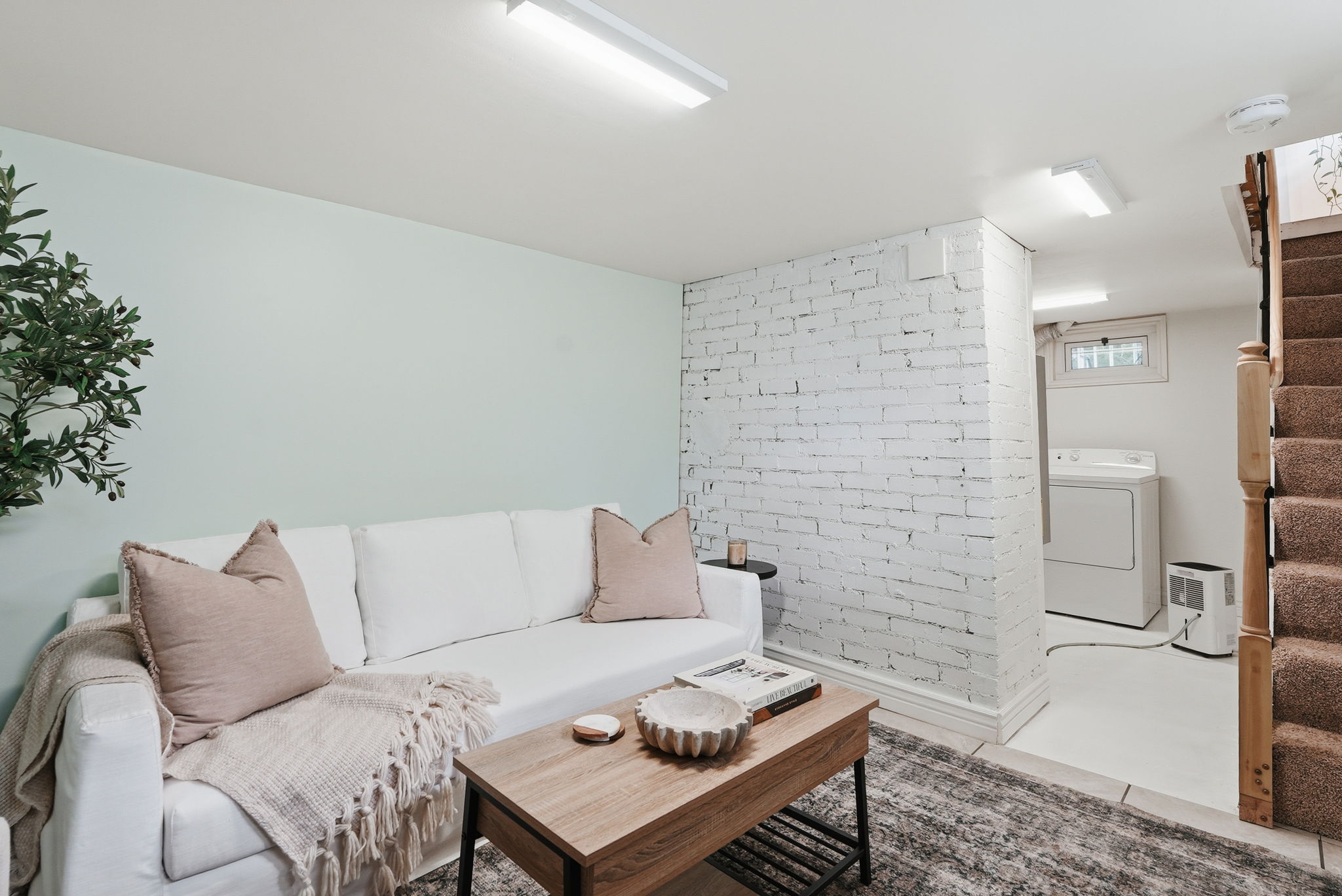 Lower level living area featuring a light-colored wall, exposed white brick accent wall, and recessed lighting