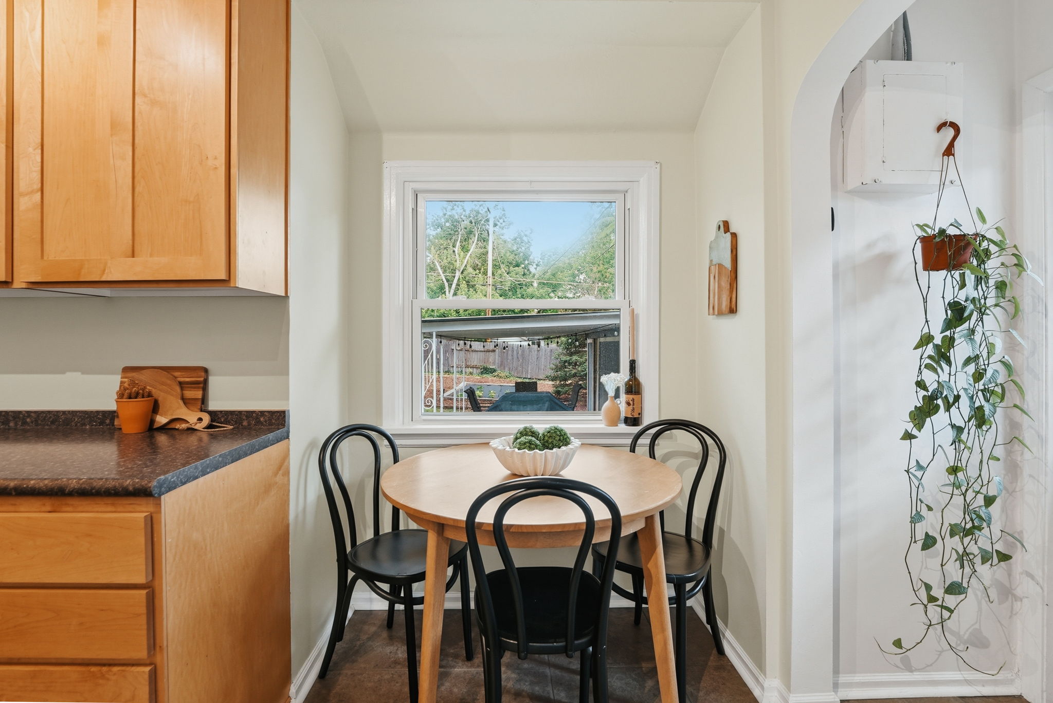 Cozy dining nook featuring a double-hung window, a light wood-finish table, and dark wood-finish flooring