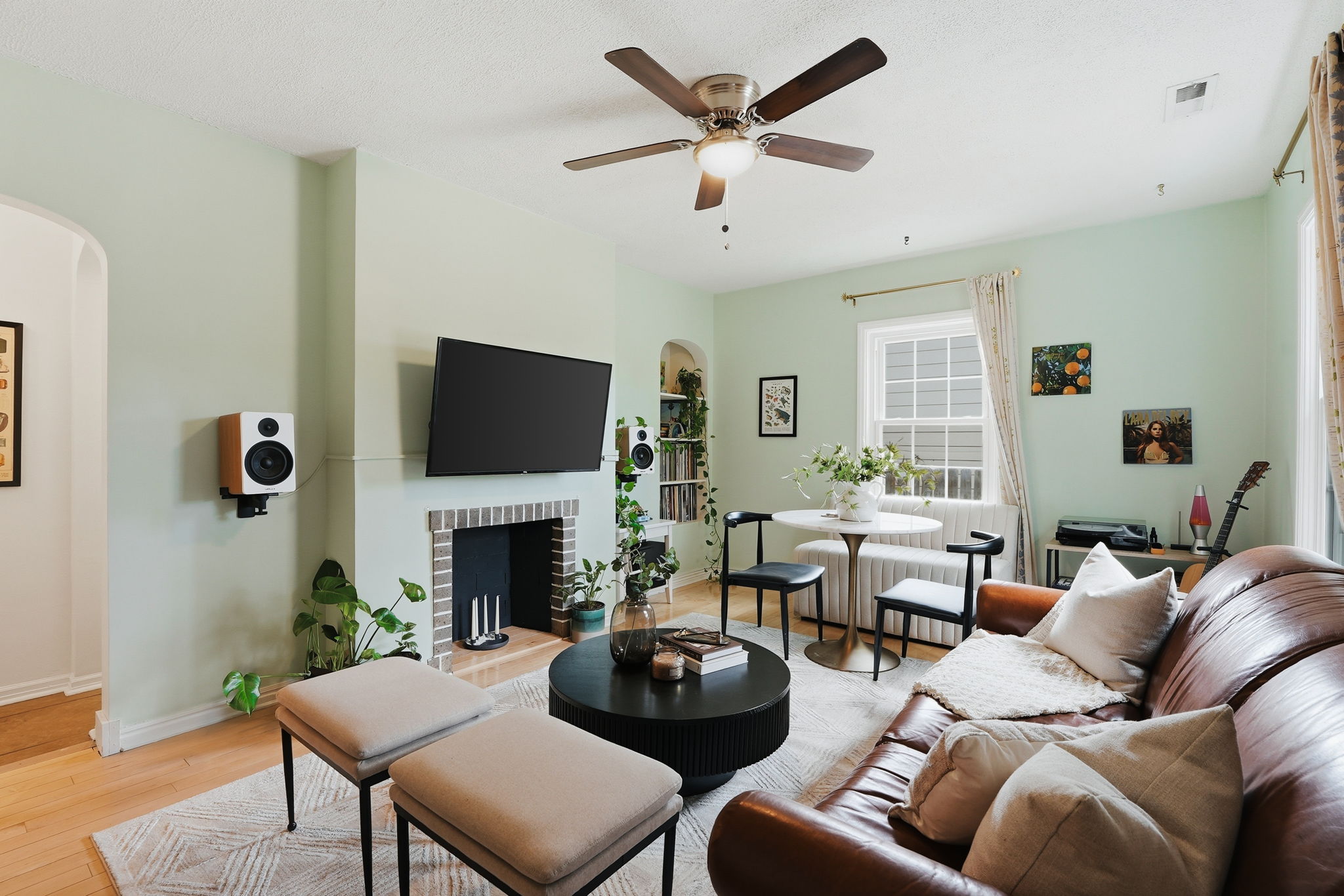 Living area featuring light green walls, wood-finish flooring, and a ceiling fan with integrated lighting