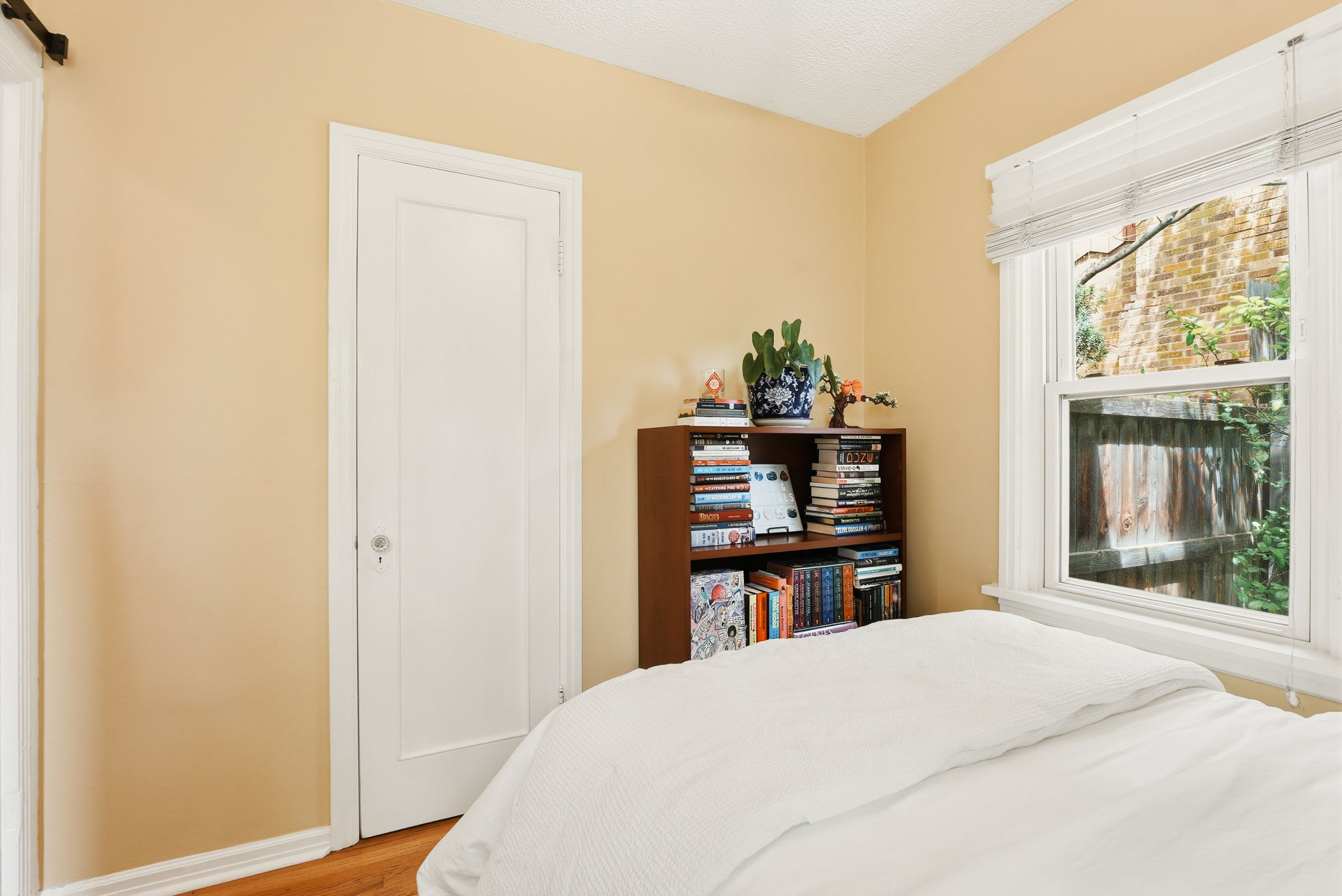 Room featuring wood-finish flooring, a single window with blinds, and light-toned walls