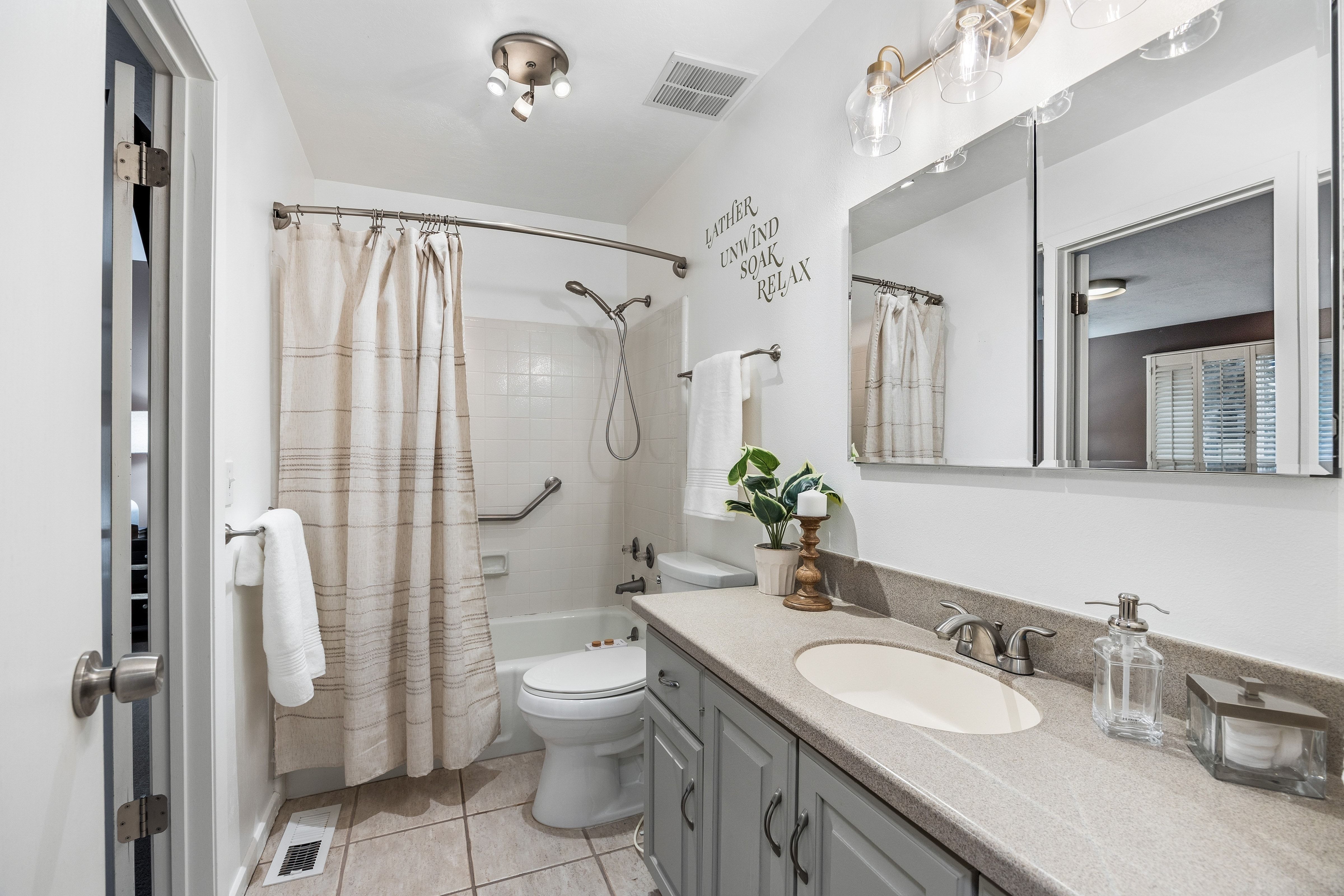 Bathroom featuring a single vanity with a light gray countertop, undermount sink, and light gray cabinet storage