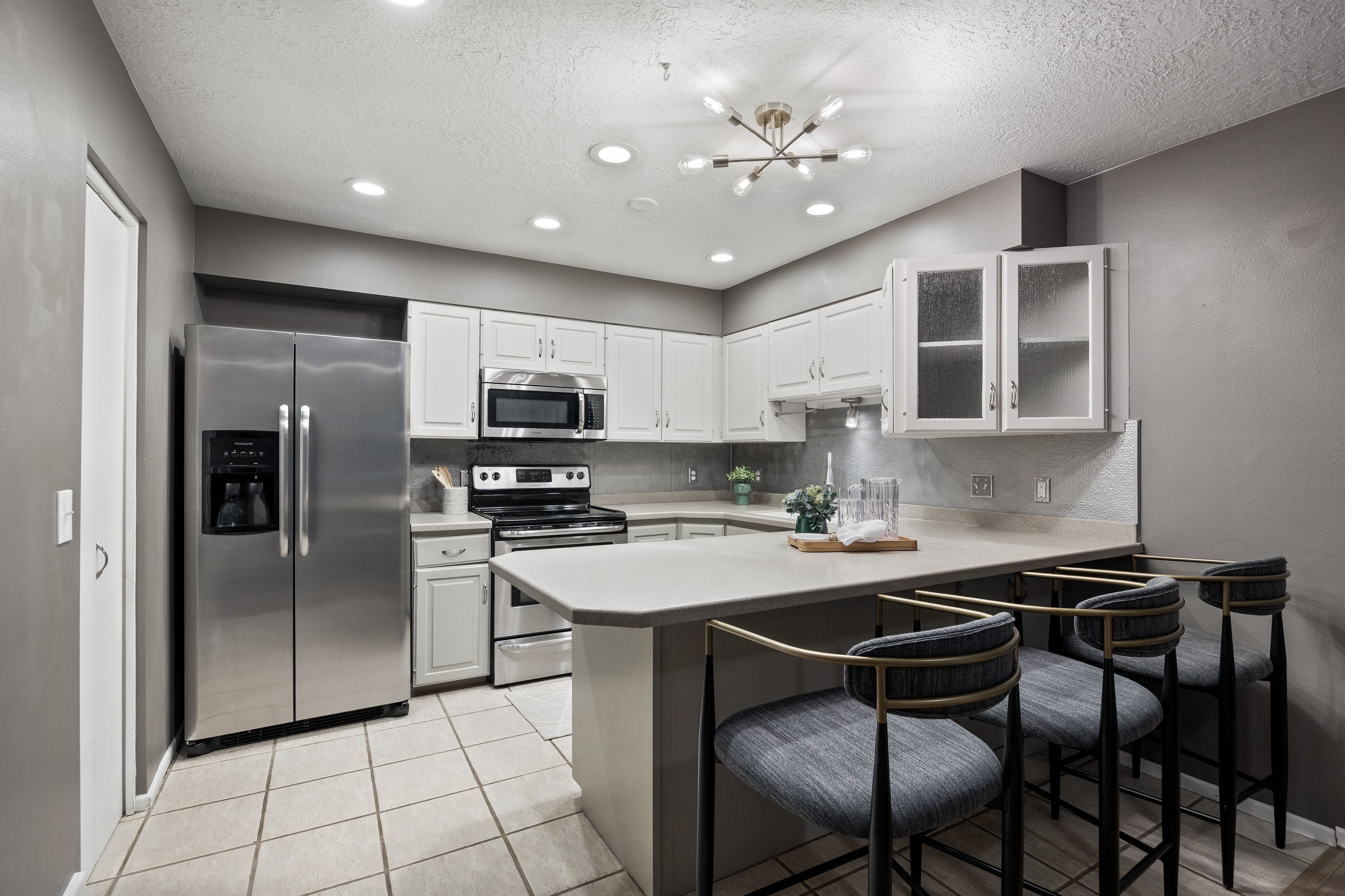 Kitchen featuring stainless steel appliances, white cabinetry, light countertops, a tile backsplash, and recessed lighting