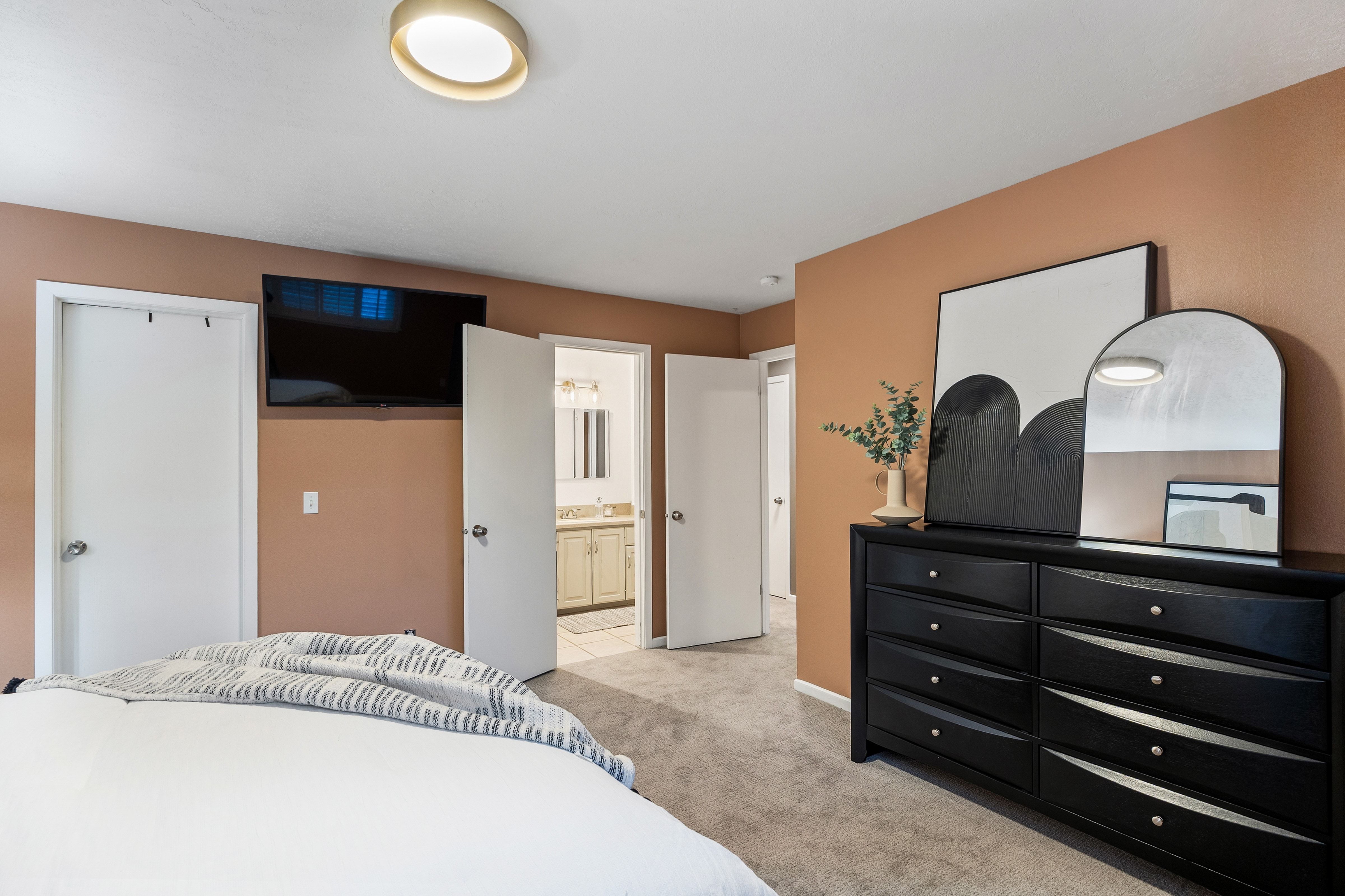 Carpeted room featuring a ceiling-mounted light fixture and a wall-mounted television