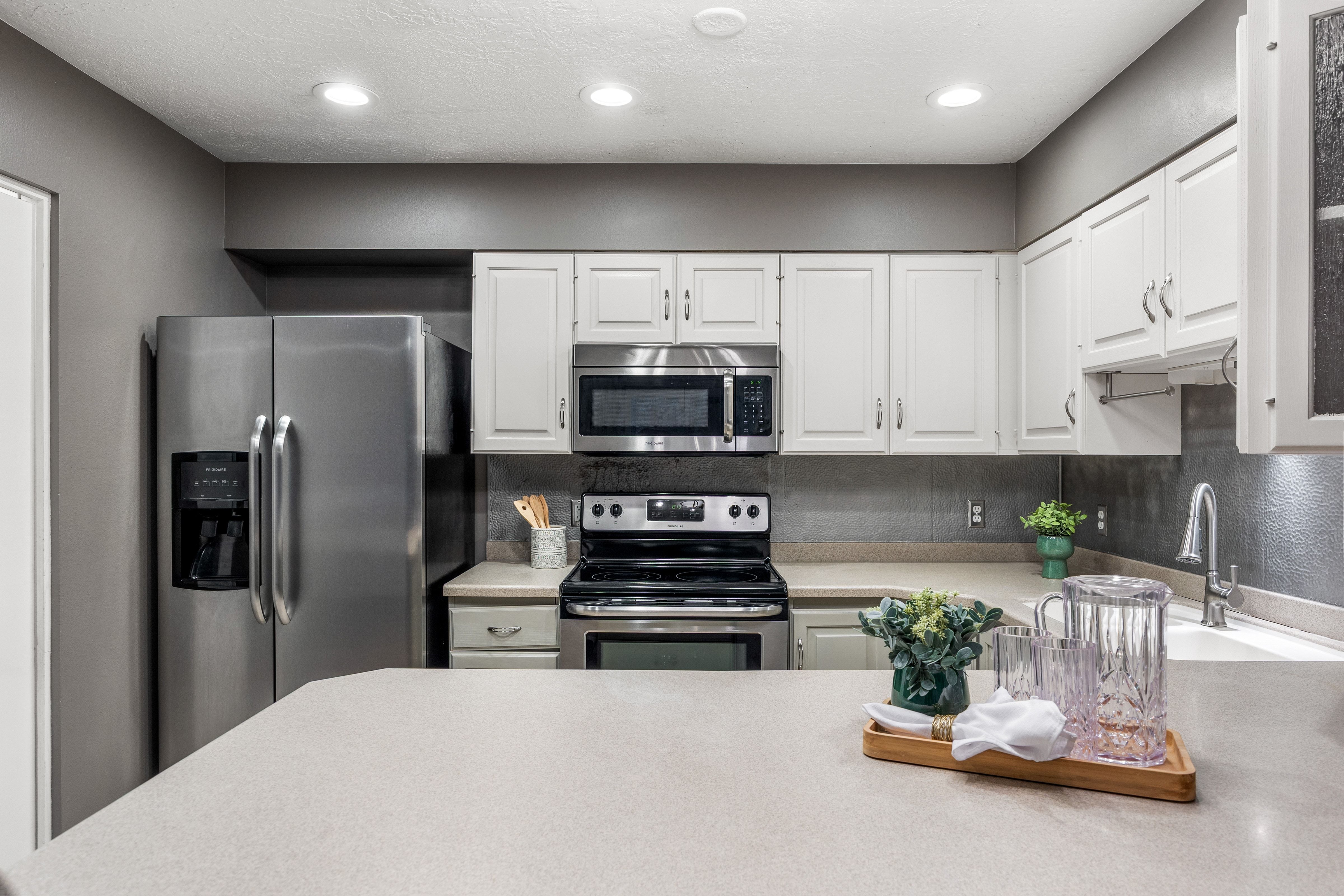 Kitchen featuring stainless steel appliances, white cabinetry, light countertops, a textured backsplash, and recessed lighting