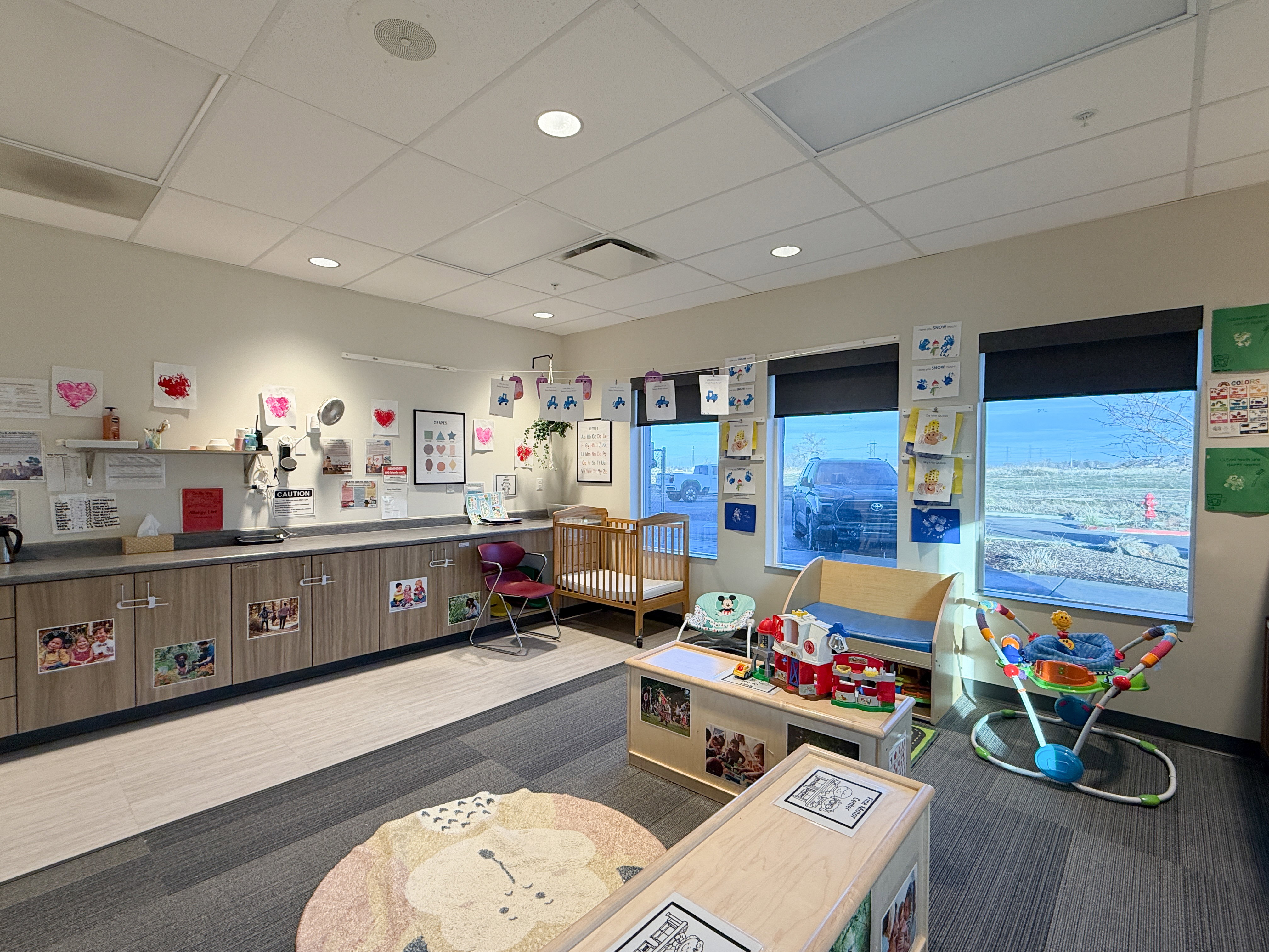 Interior space featuring a long countertop with base cabinetry, multiple windows with roller shades, recessed lighting, and a suspended ceiling