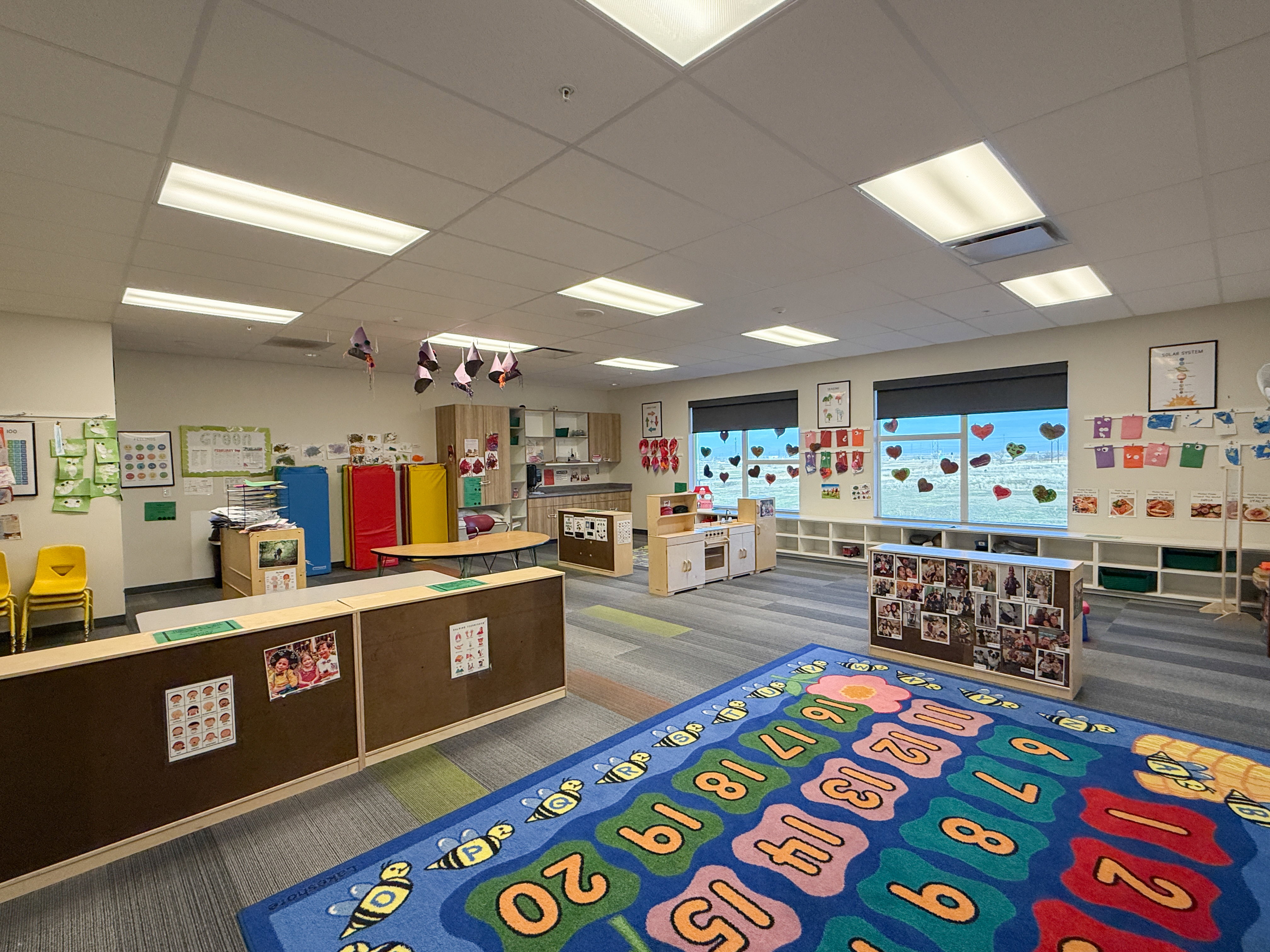 Open interior space featuring recessed ceiling lighting, two large windows with roller shades, built-in shelving, wood-finish cabinetry, and a patterned carpet