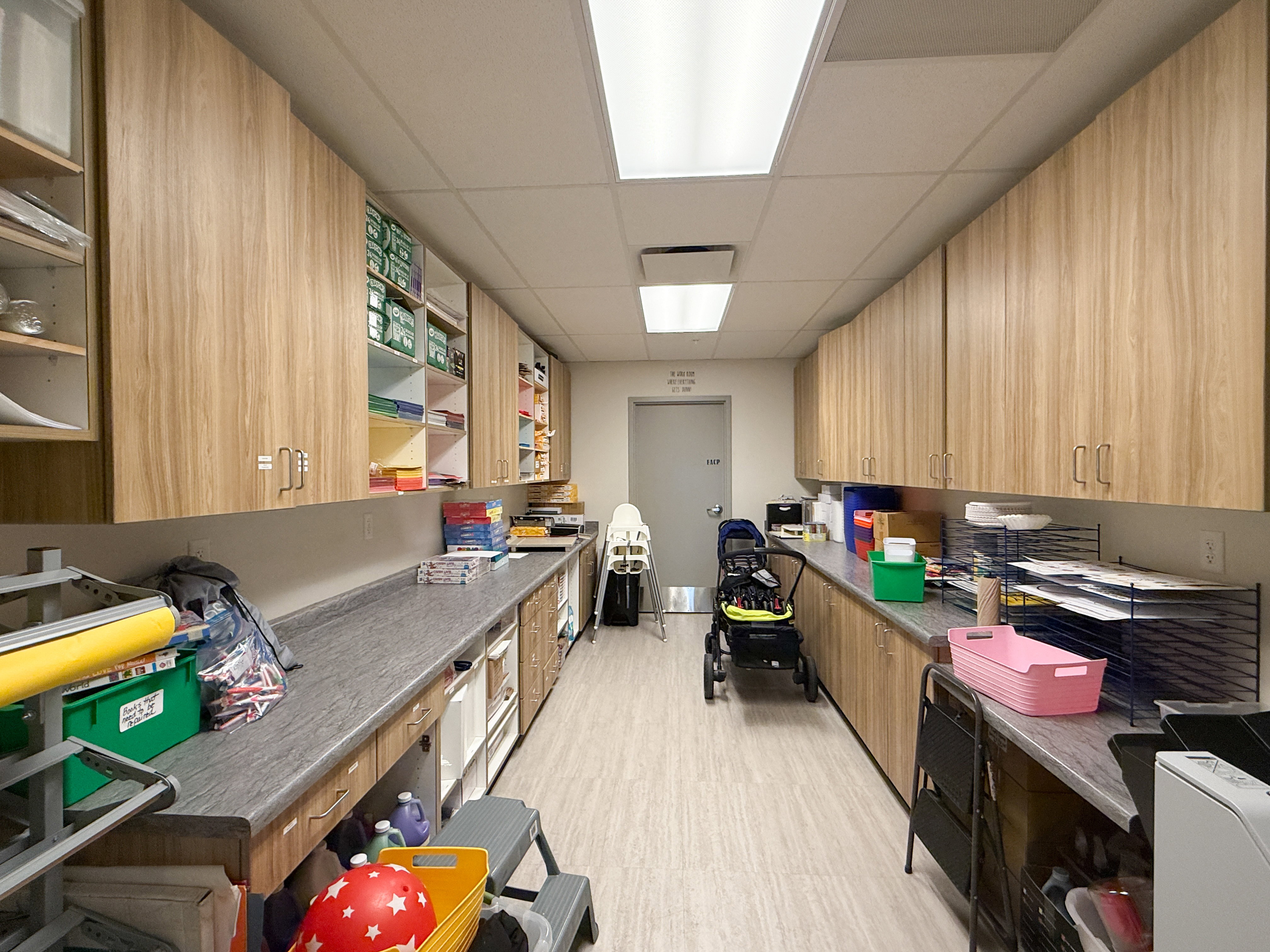 Spacious room featuring extensive wood-finish cabinetry, gray countertops, and light-colored flooring