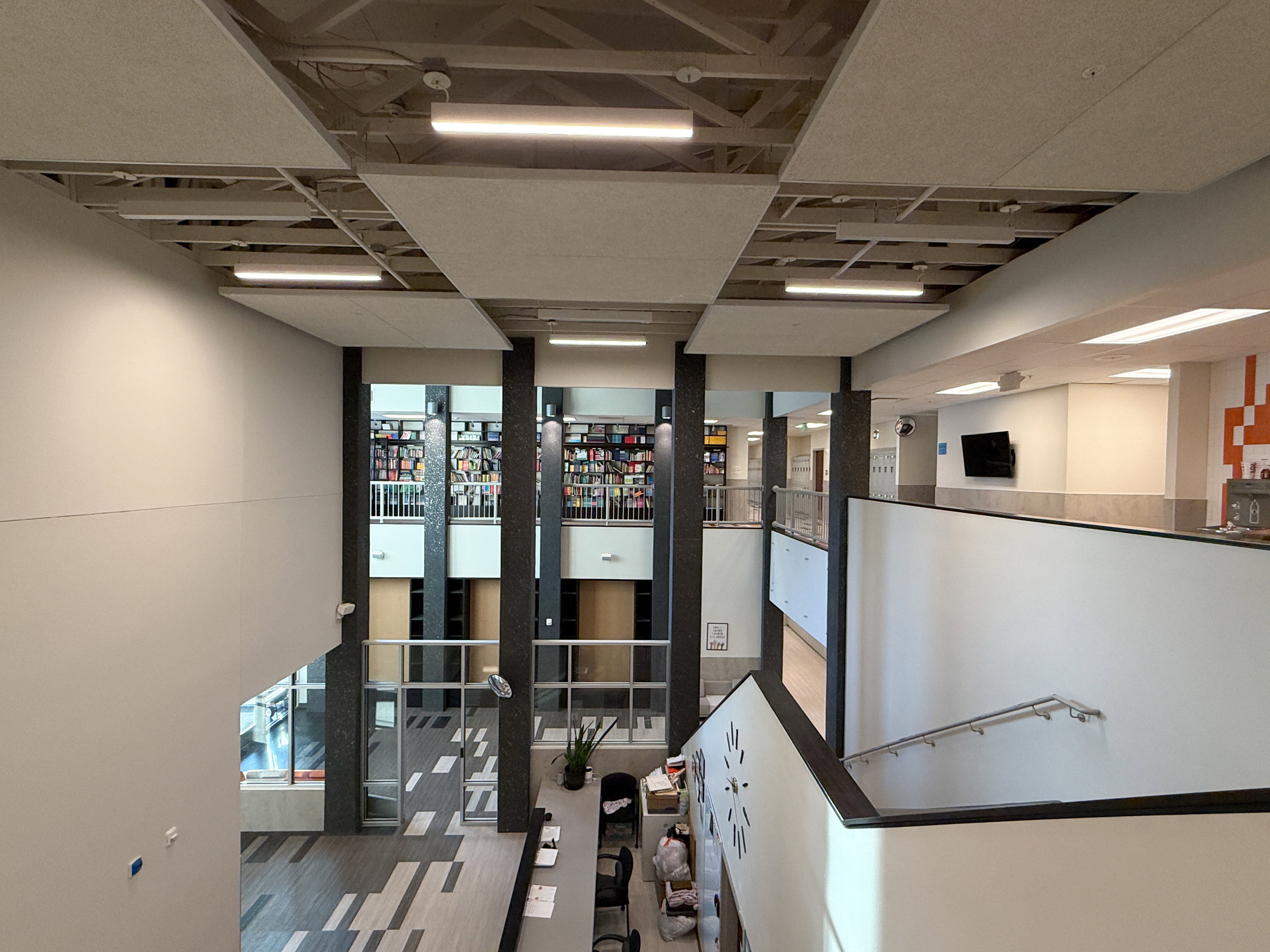 Multi-level interior space featuring linear ceiling lighting and exposed ceiling grids
