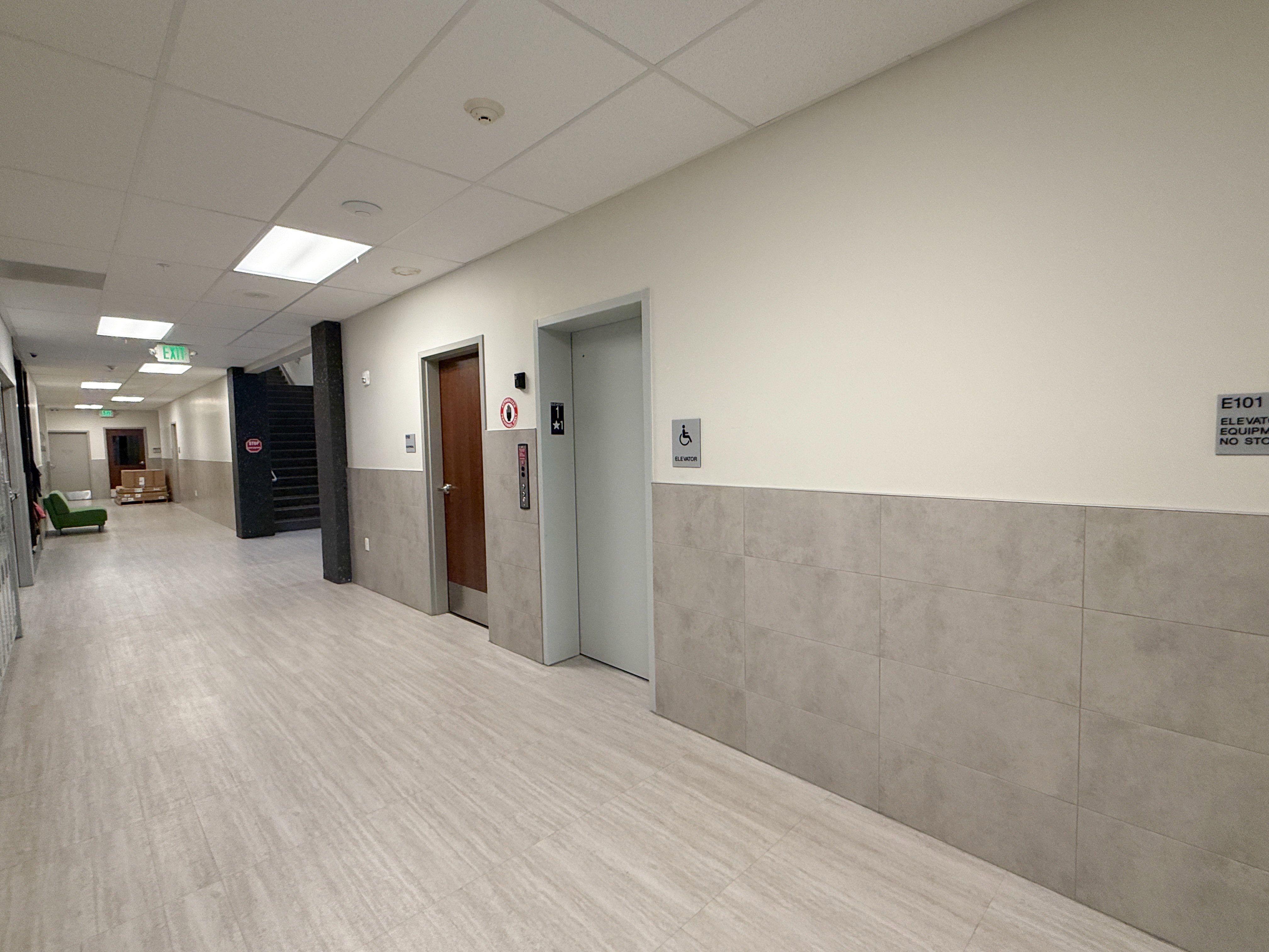 Corridor featuring light wood-finish flooring and a tiled wainscot