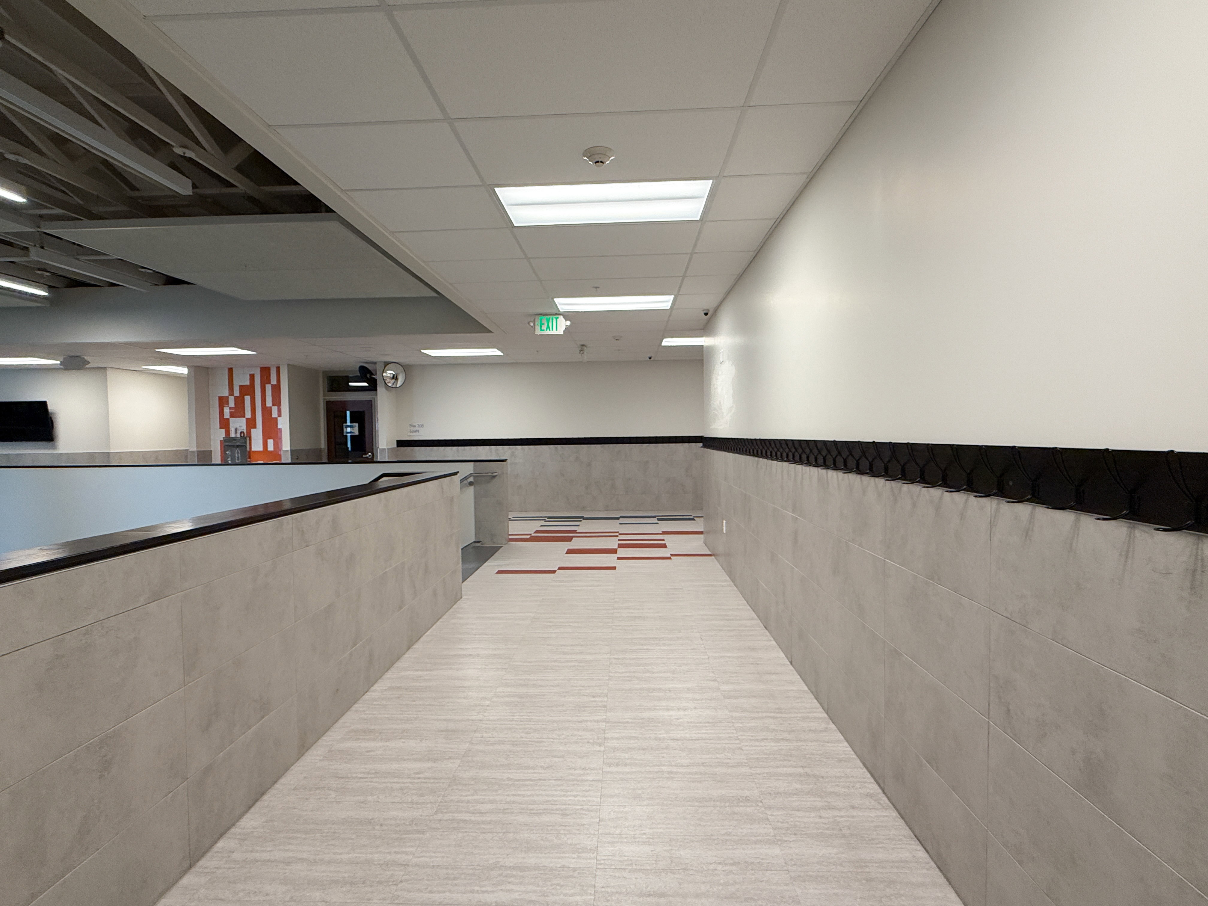 Hallway featuring light-toned tile flooring and gray wainscoting