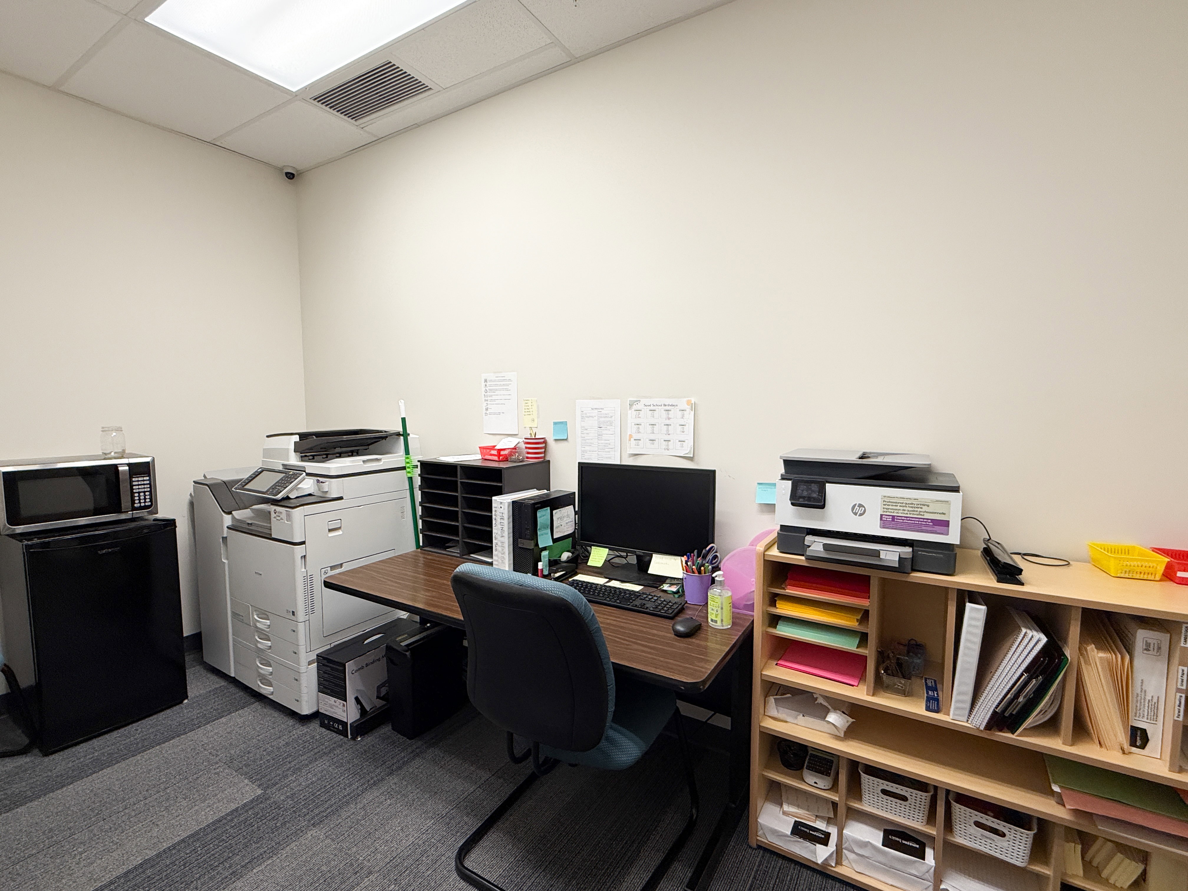 Office space featuring drop ceiling with integrated lighting, textured carpet flooring, and white painted walls