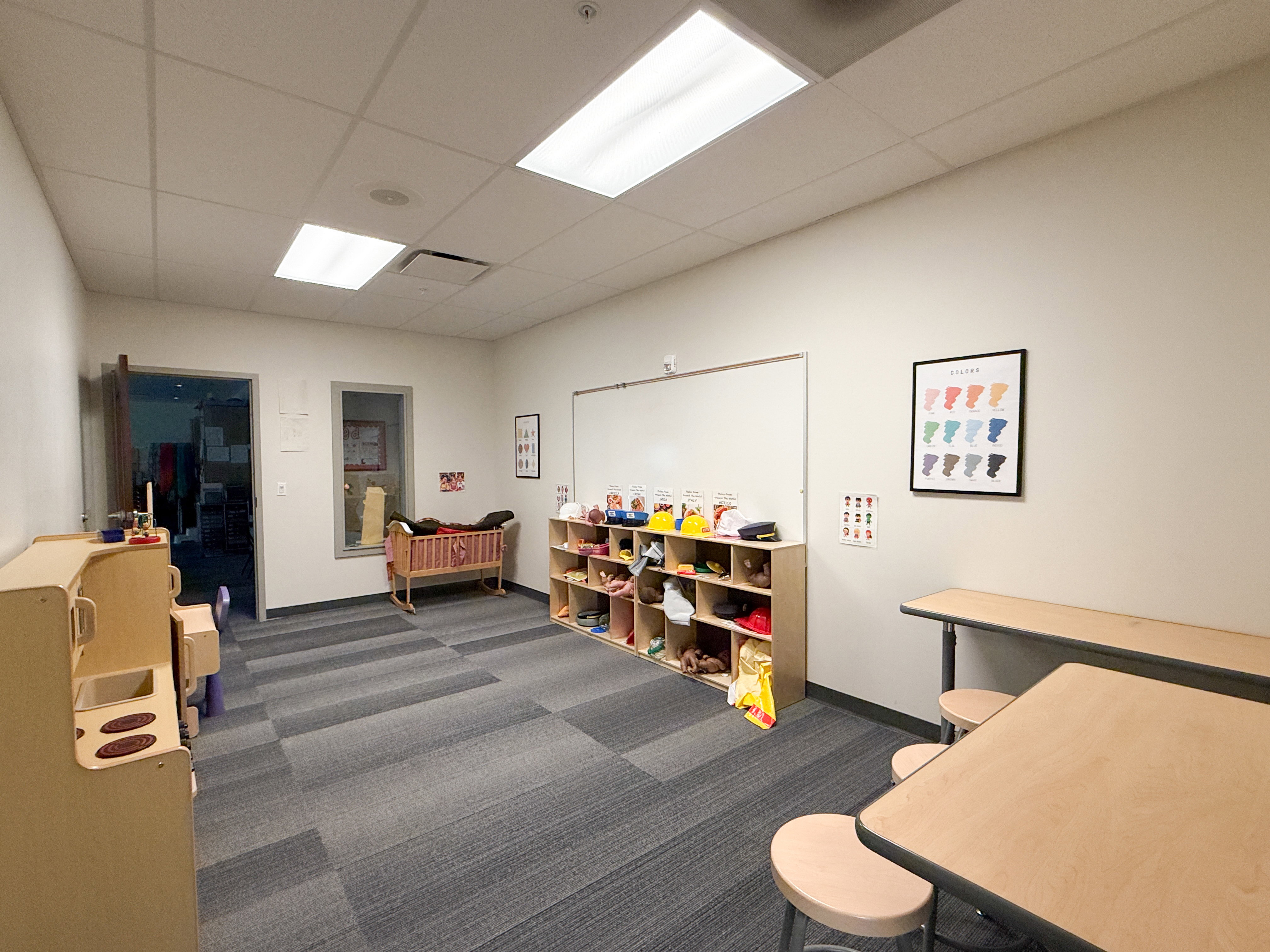 Spacious interior room featuring modular carpet tile flooring, a drop ceiling with recessed lighting, and light-toned walls